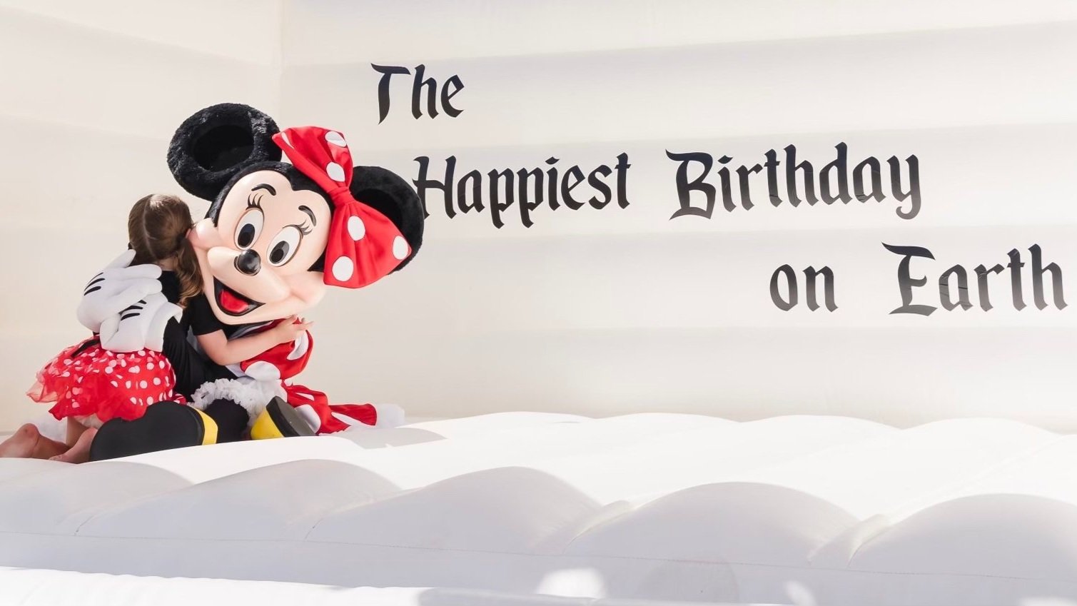 Minnie Mouse hugging a little girl in a bounce house