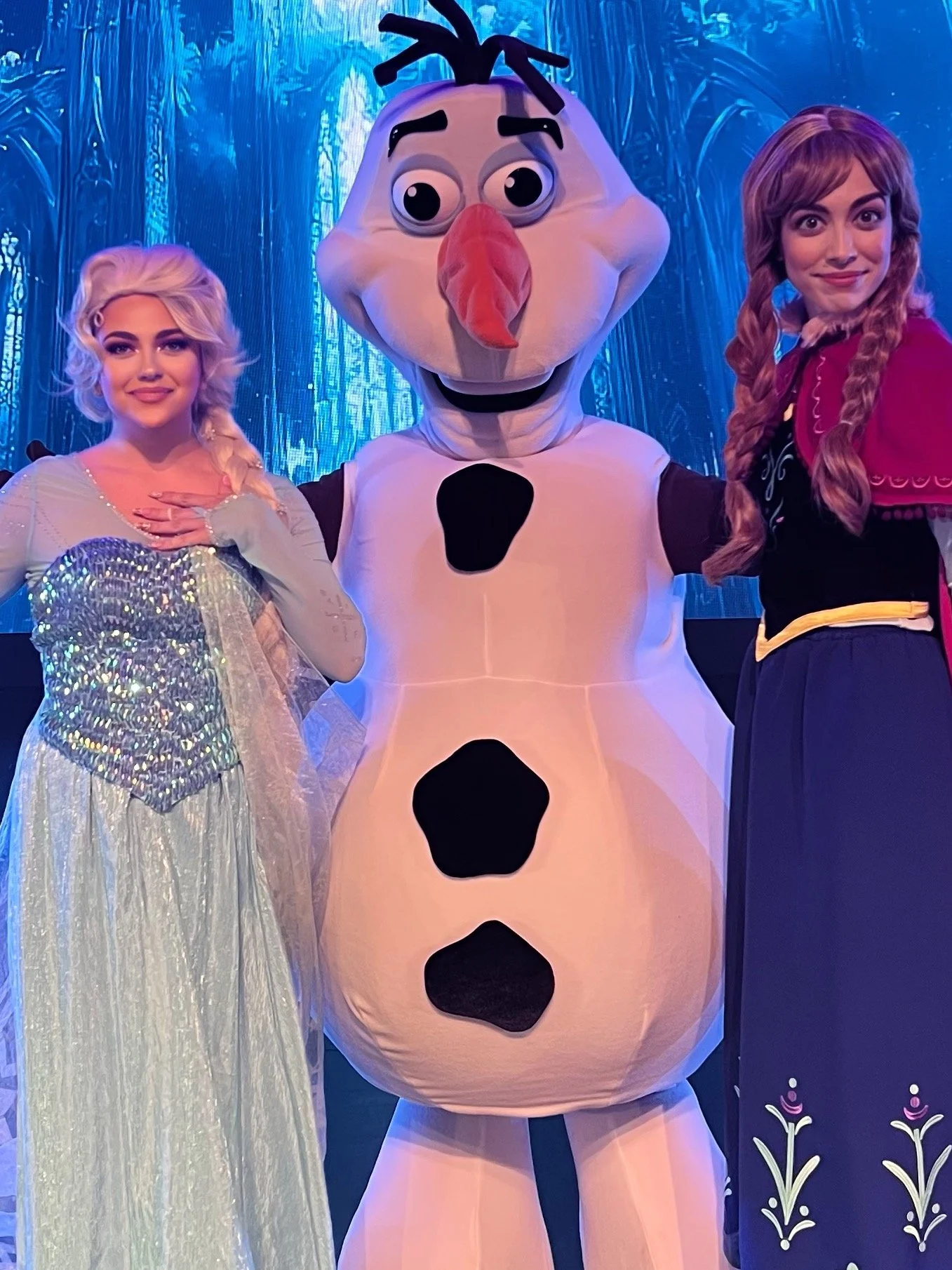 Ice Queen and Ice Princess from Frozen land standing next to their favorite Snowman at a huge Winter Celebration.