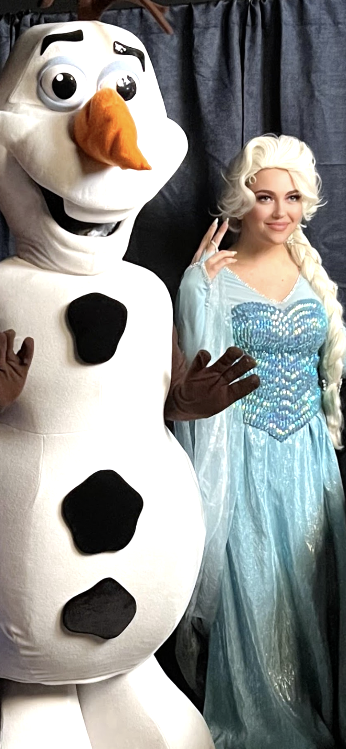 The Ice Queen from Frozen Land standing next to a Snowman Mascot at a Winter Celebration.