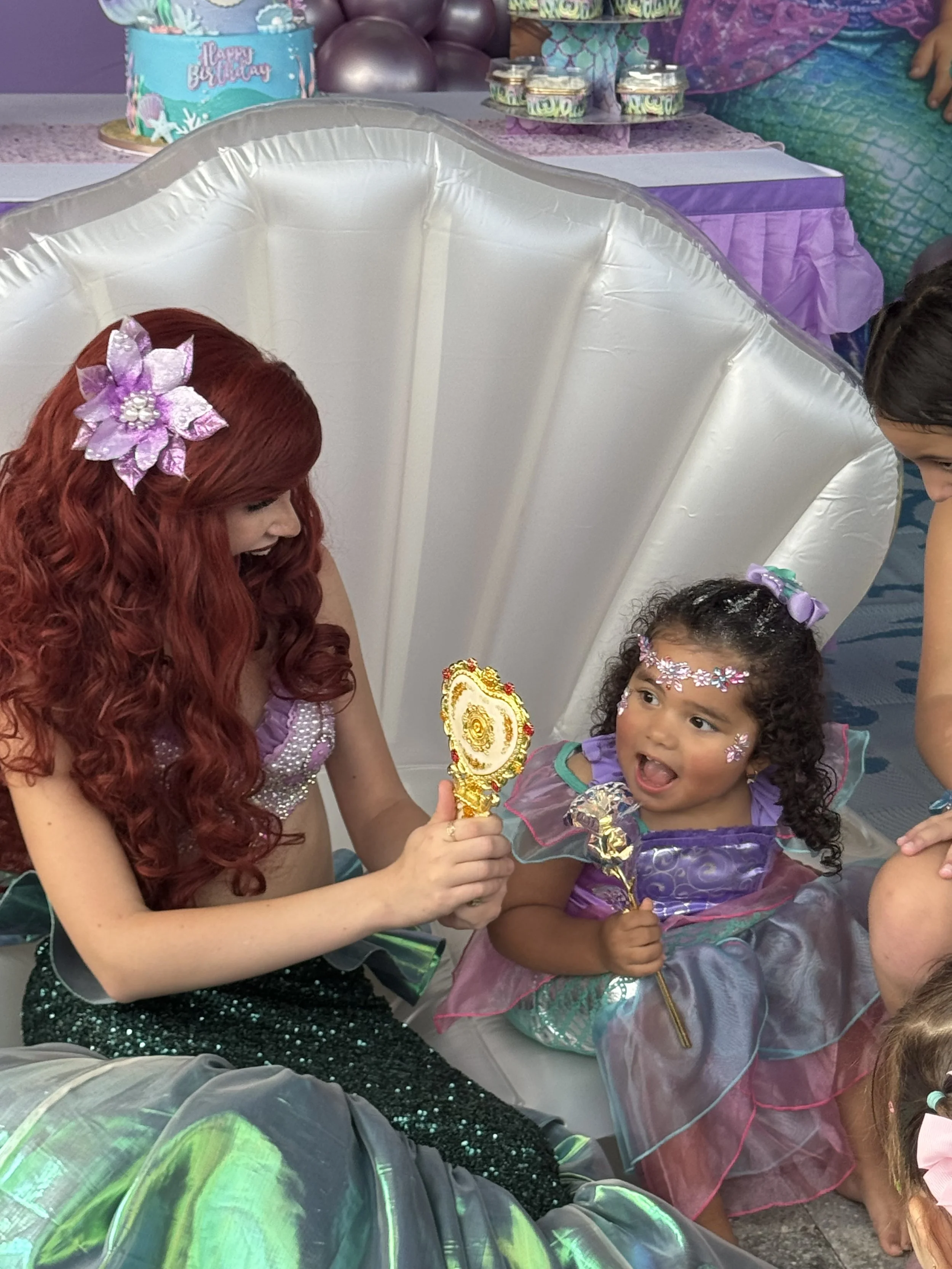 Little Mermaid applying sparkly face gems on a little girl at her birthday party in LA
