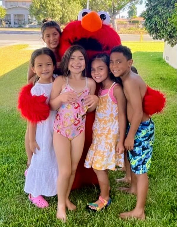 Elmo hugging a group of smiling kids