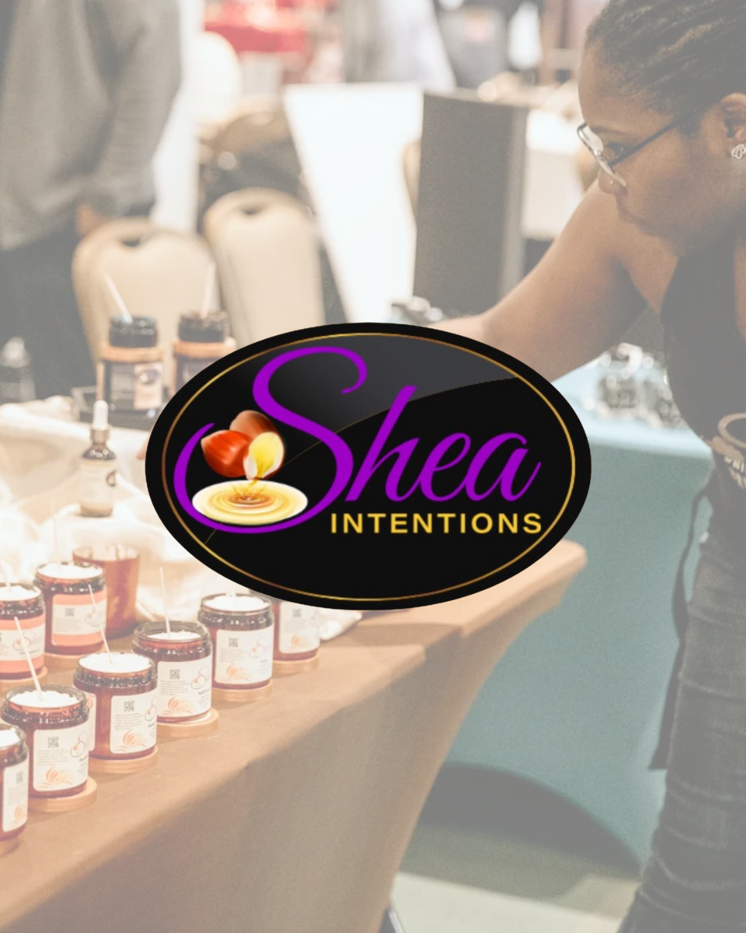 A woman at a table displaying Shea butter products with a large Shea Intentions logo overlay in the foreground.