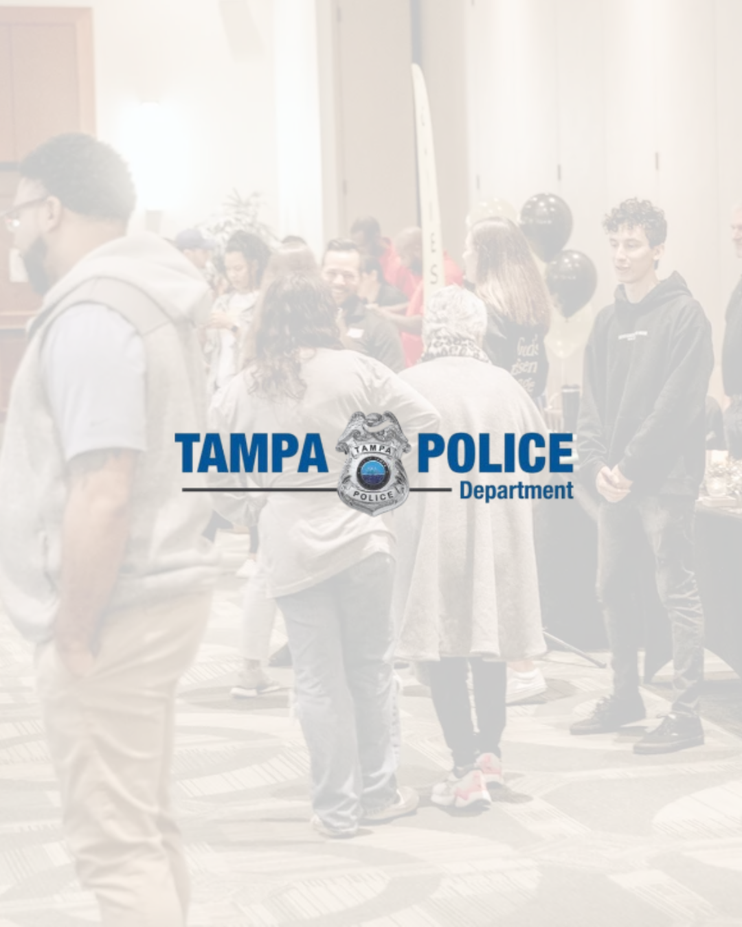 Group of people at an event, with a banner reading 'Tampa Police Department' in the foreground.
