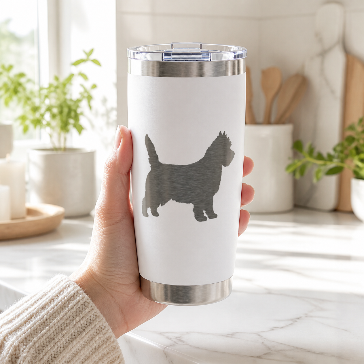 Hand holding the white engraved Cairn Terrier tumbler in a bright kitchen