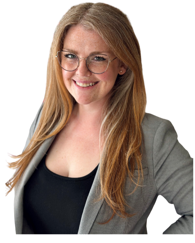 A young woman with long red hair, wearing glasses, a gray blazer, and a black top, smiling at the camera.