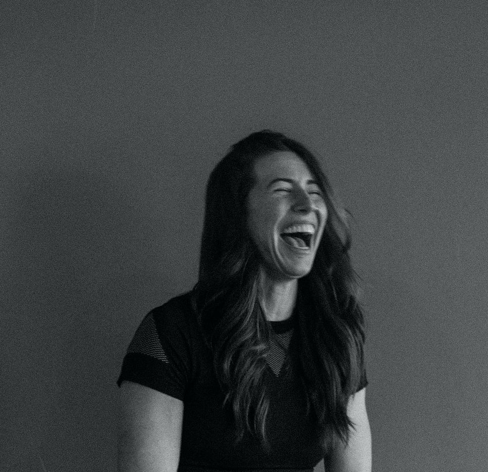 A black and white photo of a white woman with dark hair laughing
