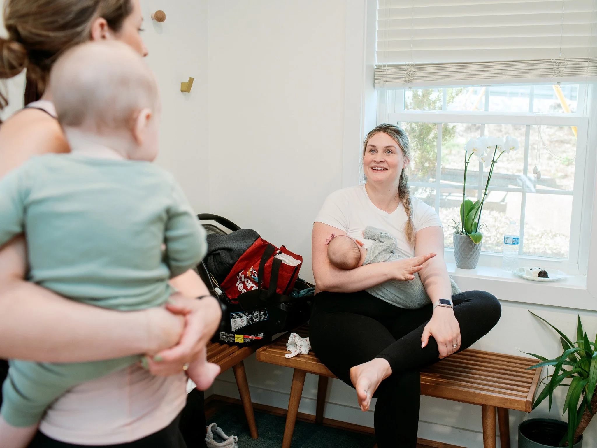 Two women standing in the Kindred lobby area, holding babies and talking