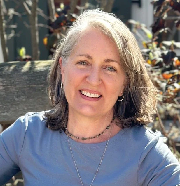 Photo of white woman with shoulder length gray hair wearing a lavender top