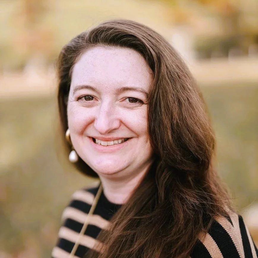 White woman with brown hair and brown eyes in a striped shirt smiling