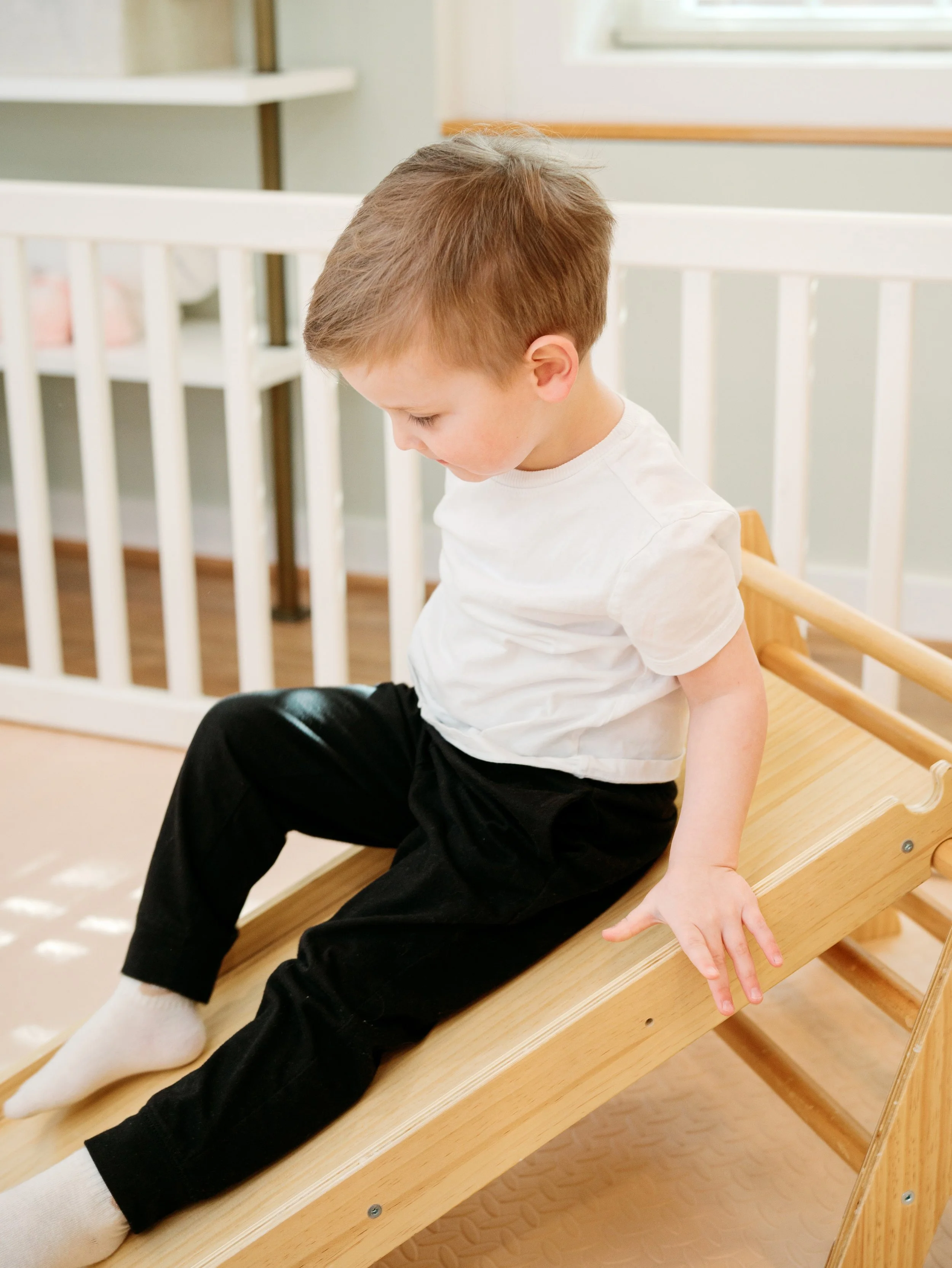 A child sitting on a wooden slide in the studio 