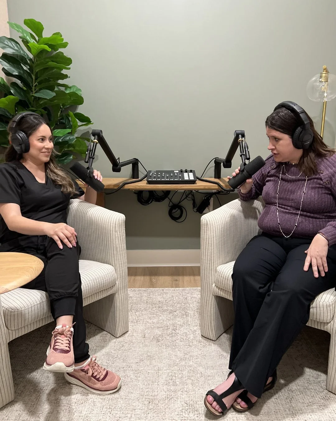 Dark haired woman in scrubs and pink shows hosting a podcast