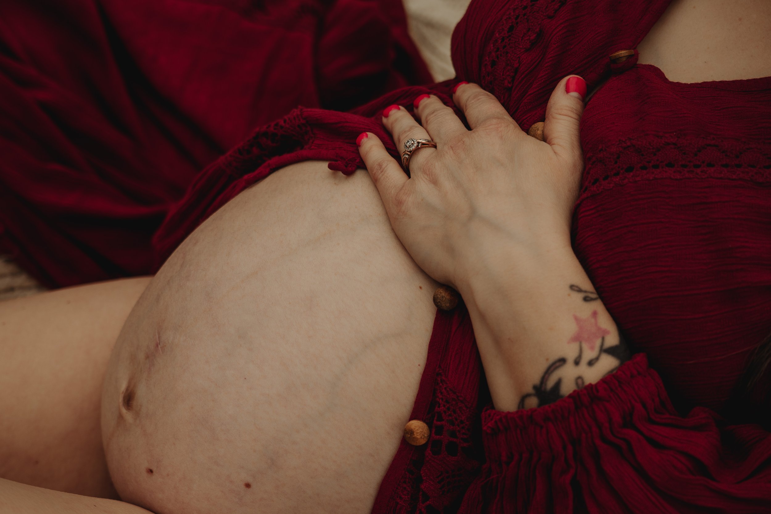 Close up on baby bump with momma's hand on the top of her belly.