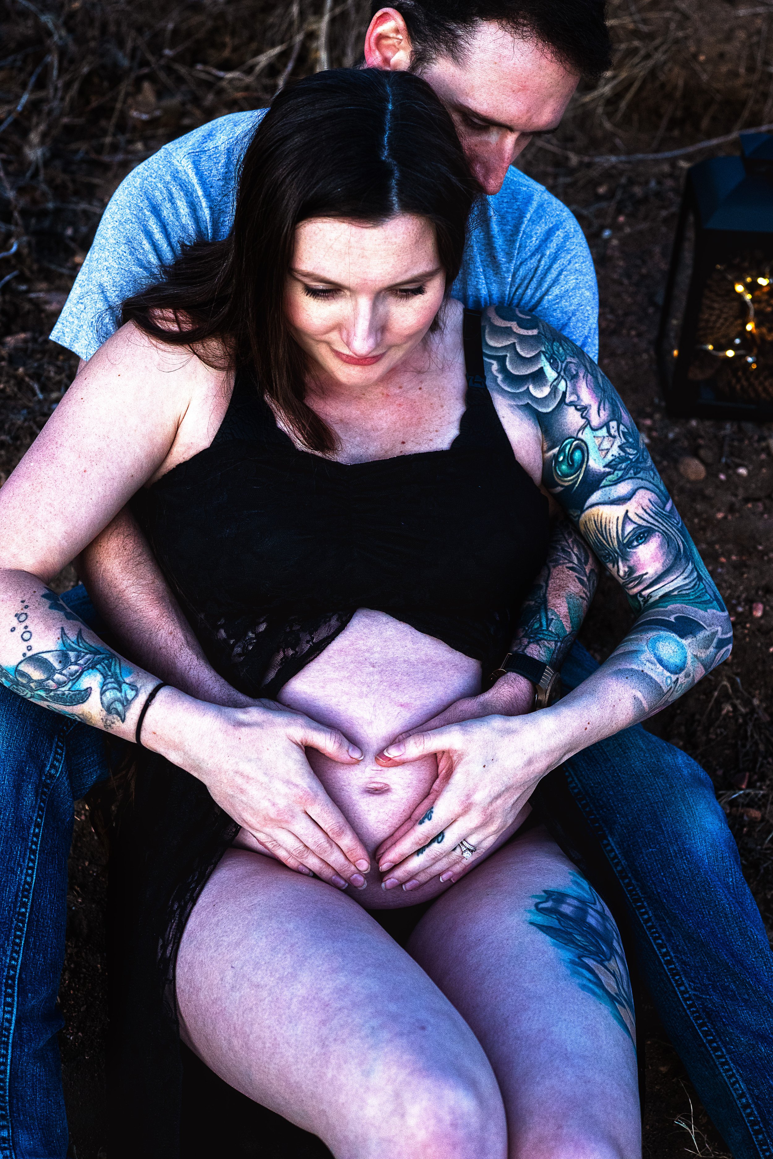 Embracing baby bump with heart shaped hands around belly button