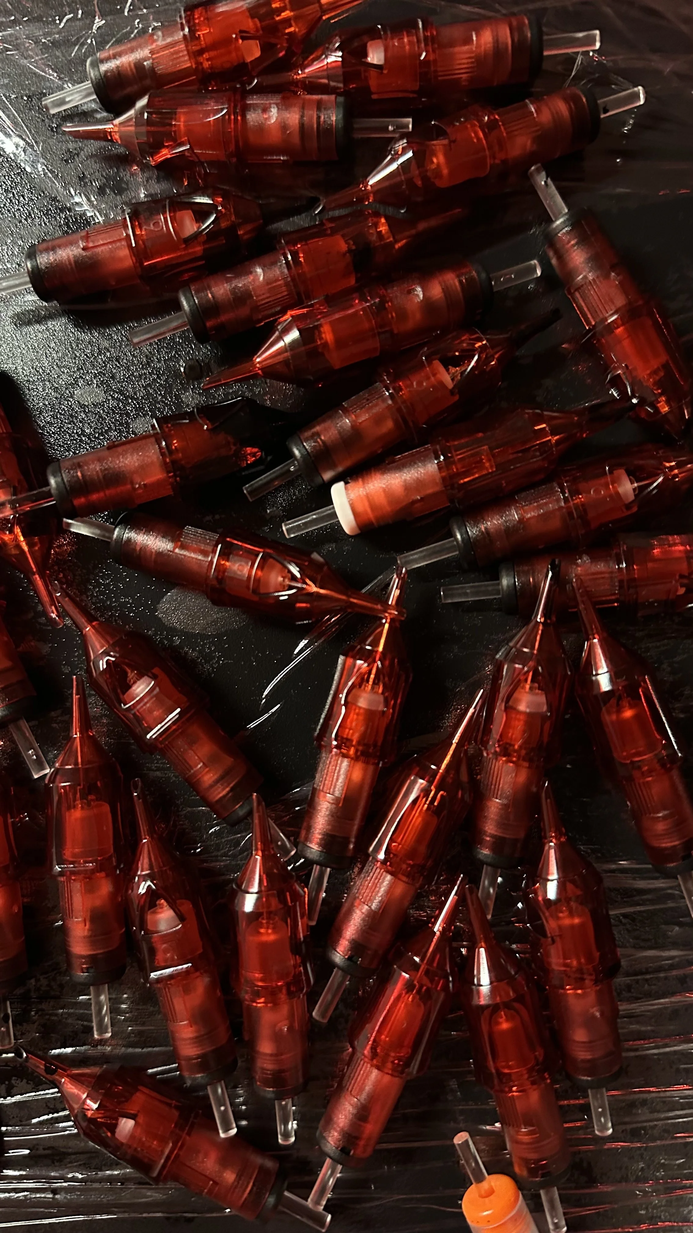 Cartouches d'aiguilles de tatouage dans l'atelier de Coriolis, lumière rouge