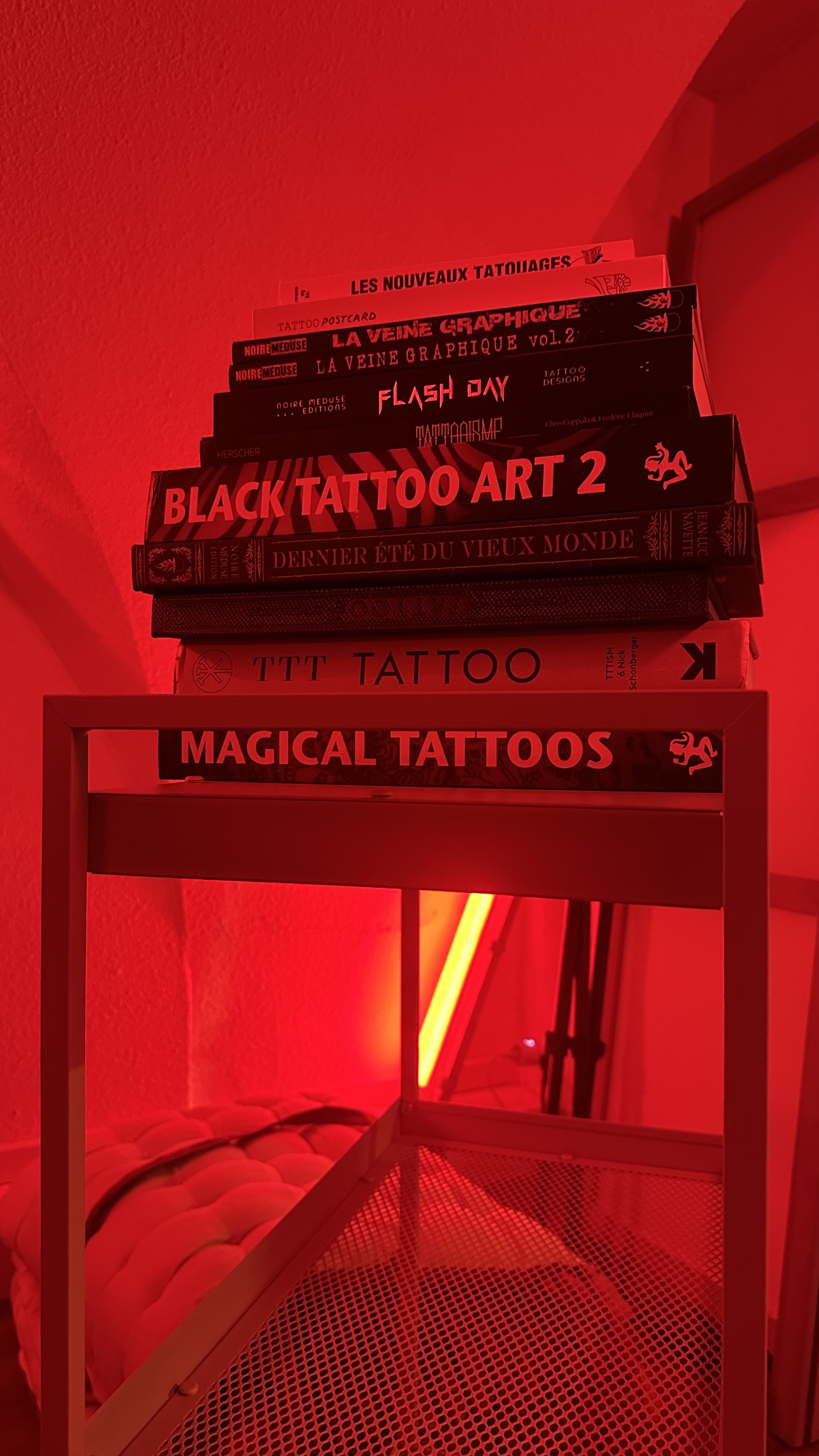 Pile de livres d'art tatouage dans l'atelier de Coriolis, lumière rouge