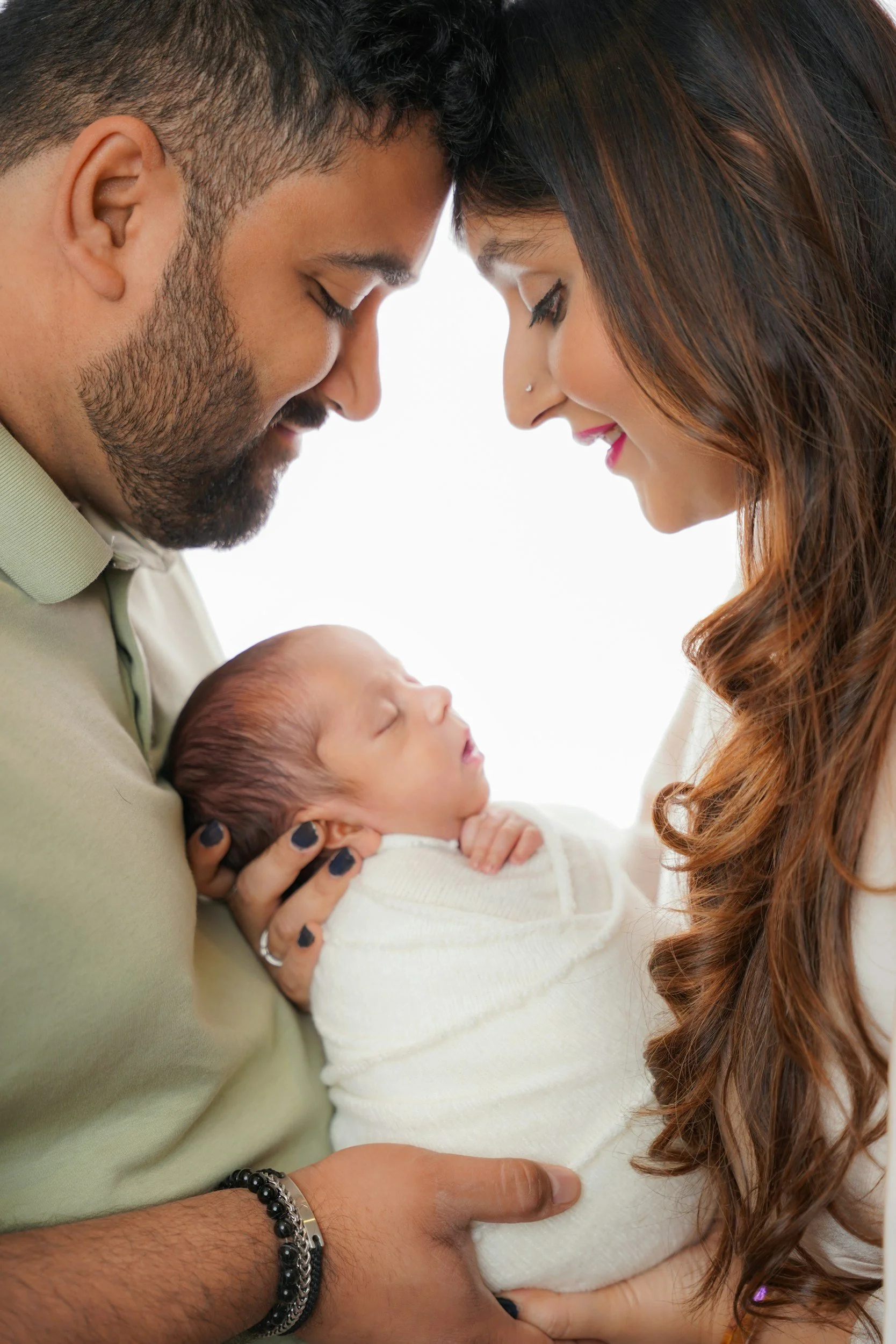 baby displays sensory organization while swaddled in white blanket, mom and dad holding infant for containment, consoling, hands to midline, newborn support