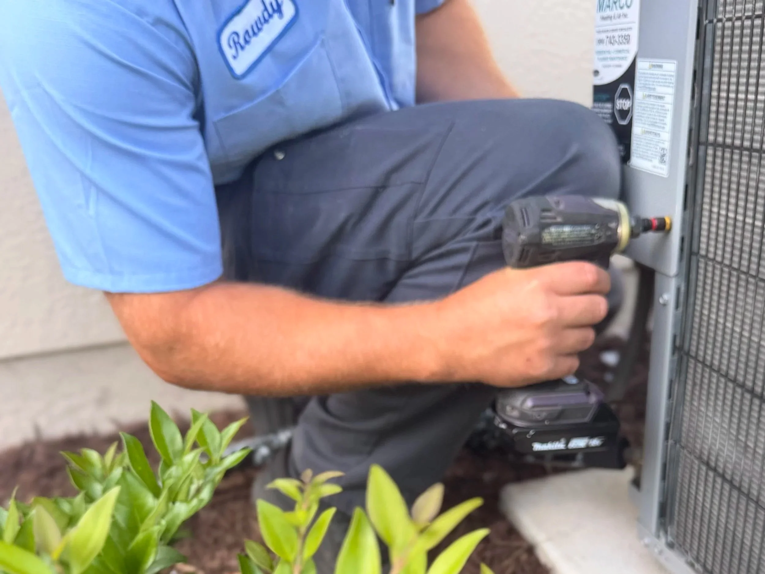 Technician installing or repairing an outdoor HVAC unit with a cordless drill.