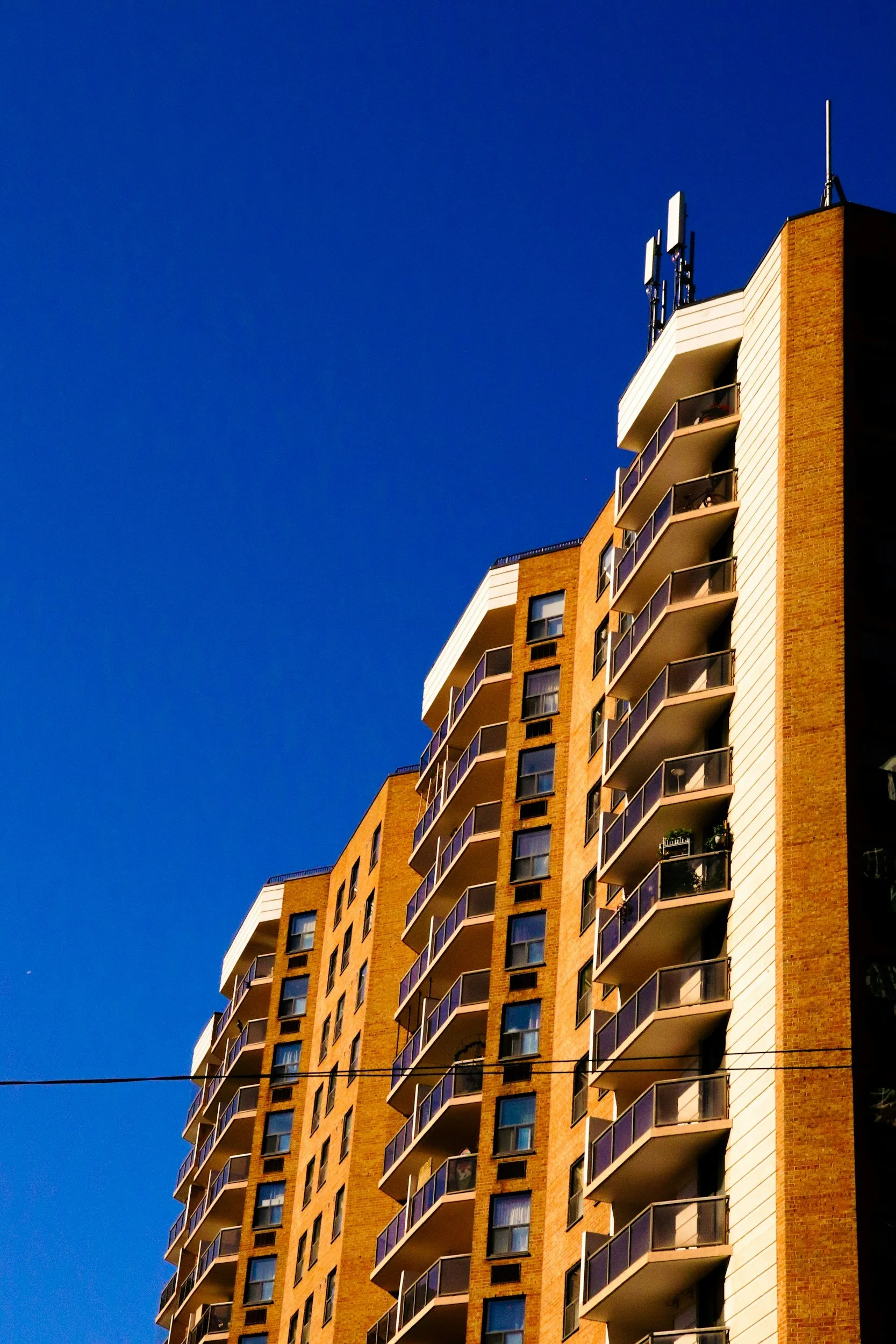 A brick high-rise apartment building with balconies and original sealed unit windows