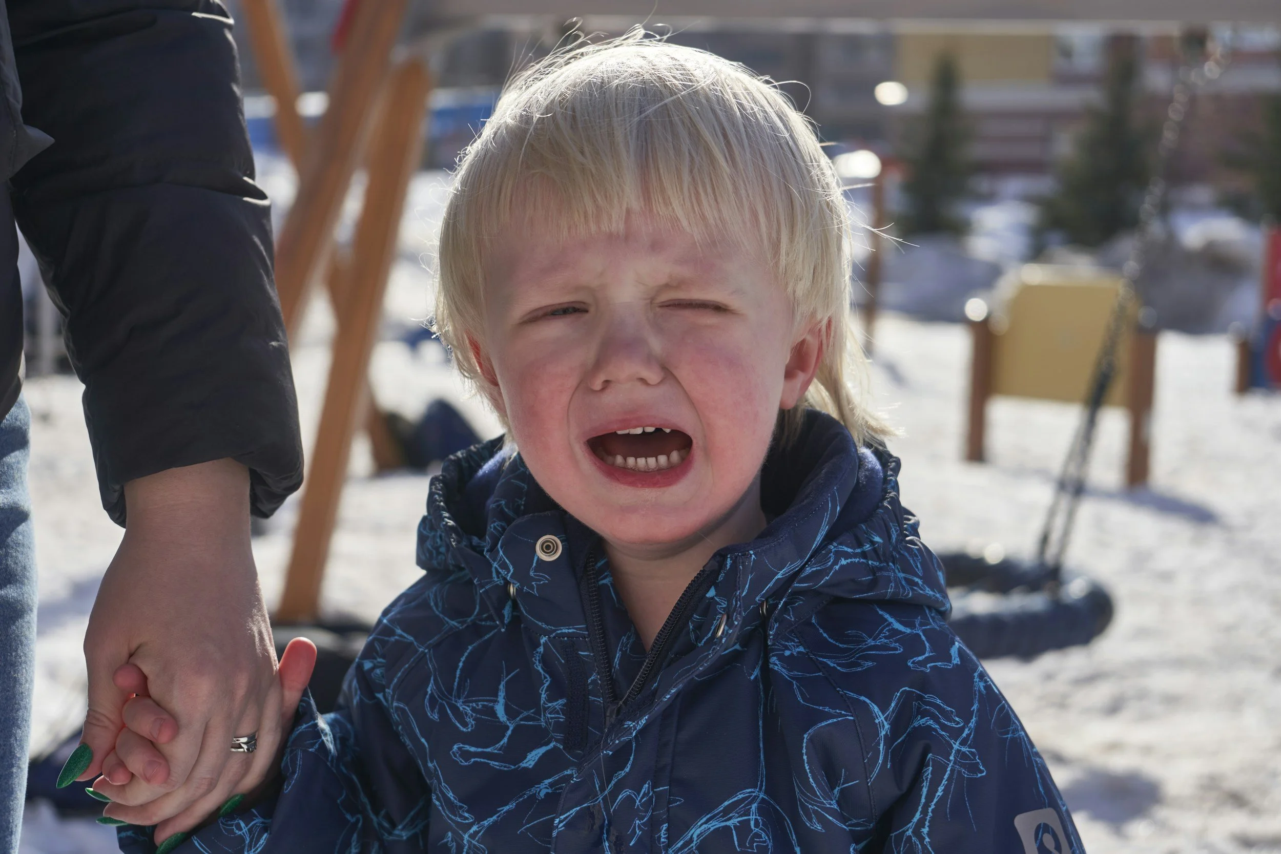 Parent comforting an overwhelmed child after school while discussing emotional regulation and school stress with a therapist