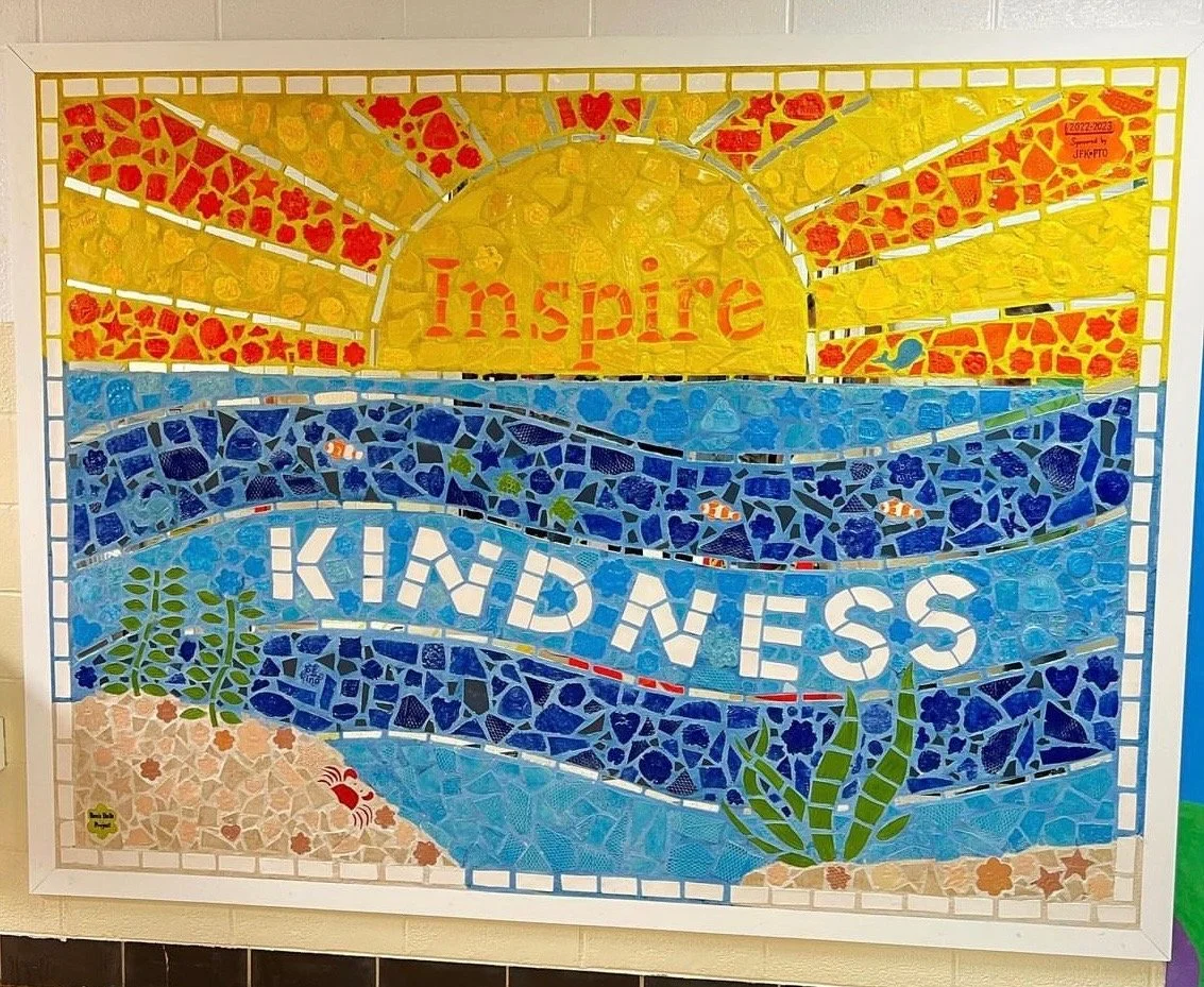 Colorful mosaic poster with the words 'Inspire Kindness' and a sun rising over blue waves, decorated with flowers and seaweed.