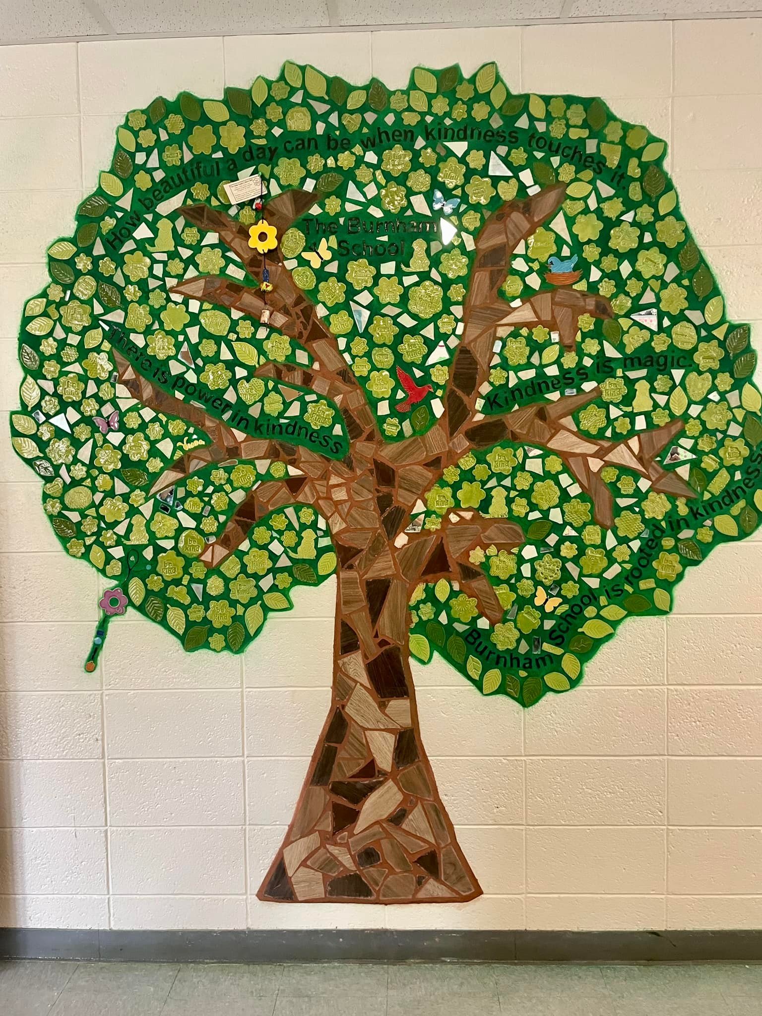Decorative mosaic of a tree made from cut-out paper on a wall, with words like 'kindness' and 'power' written on it.