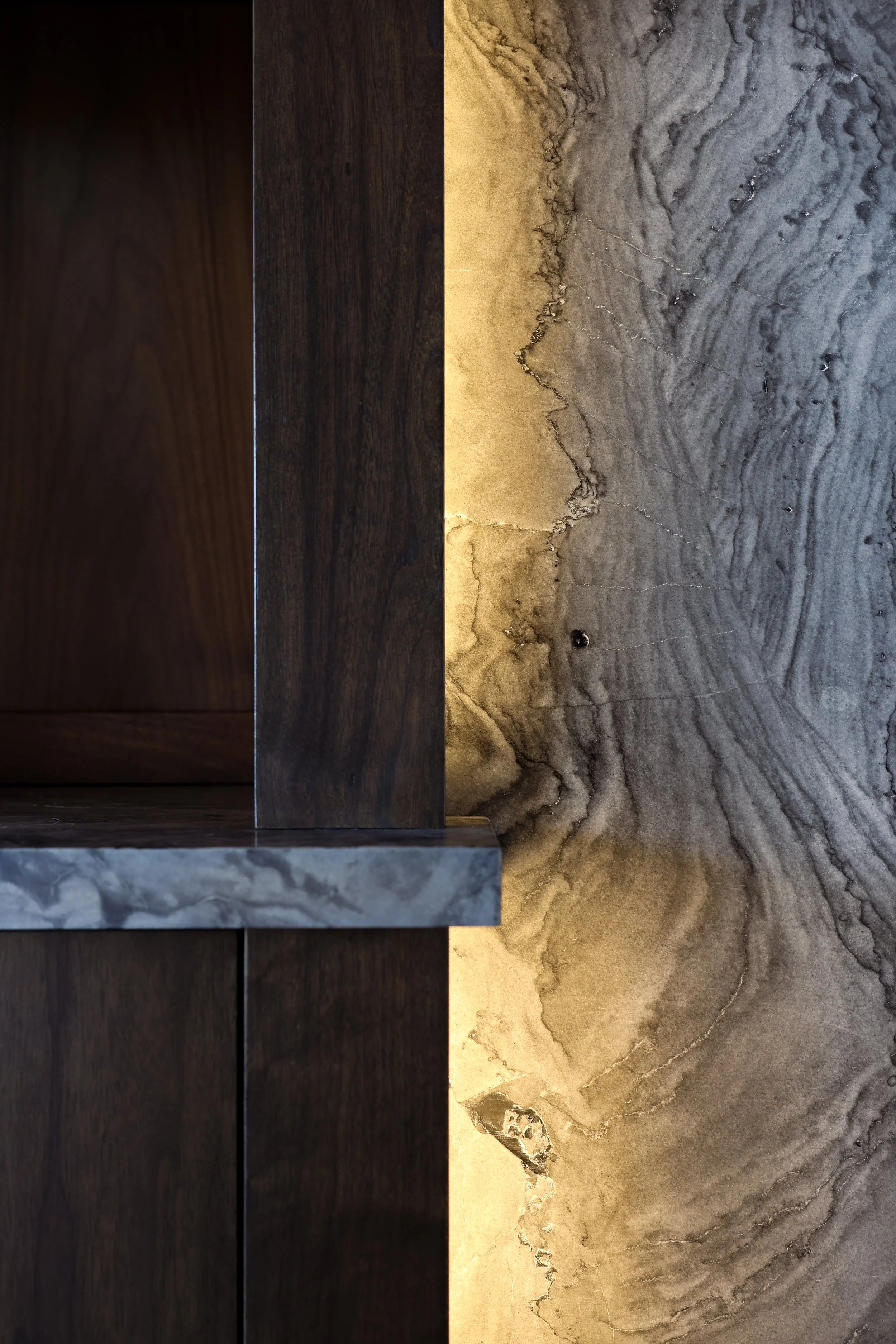 Close-up view of a textured surface with a combination of dark wood and marble with gold and gray tones.