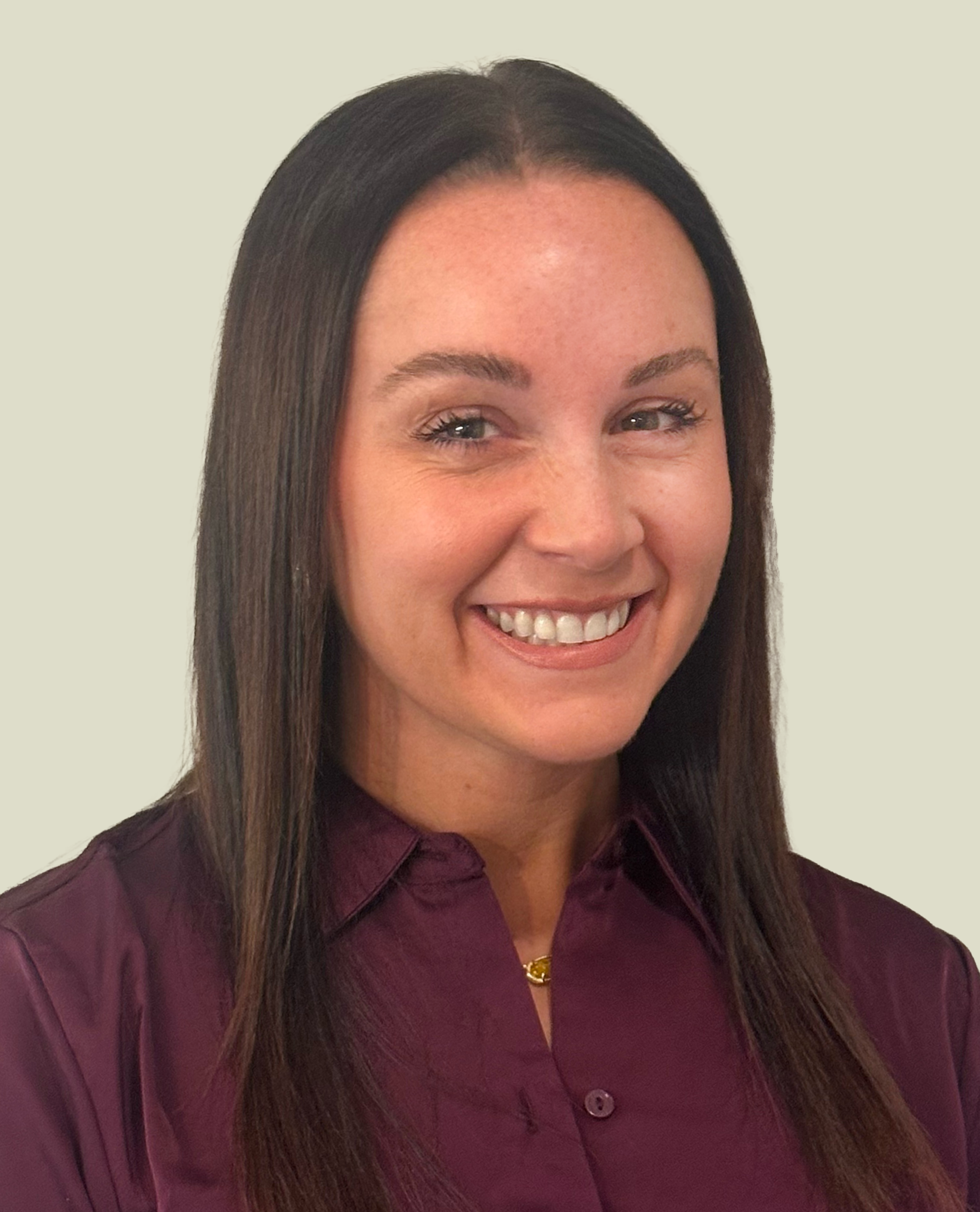 A smiling woman with long dark hair wearing a maroon shirt against a plain background.
