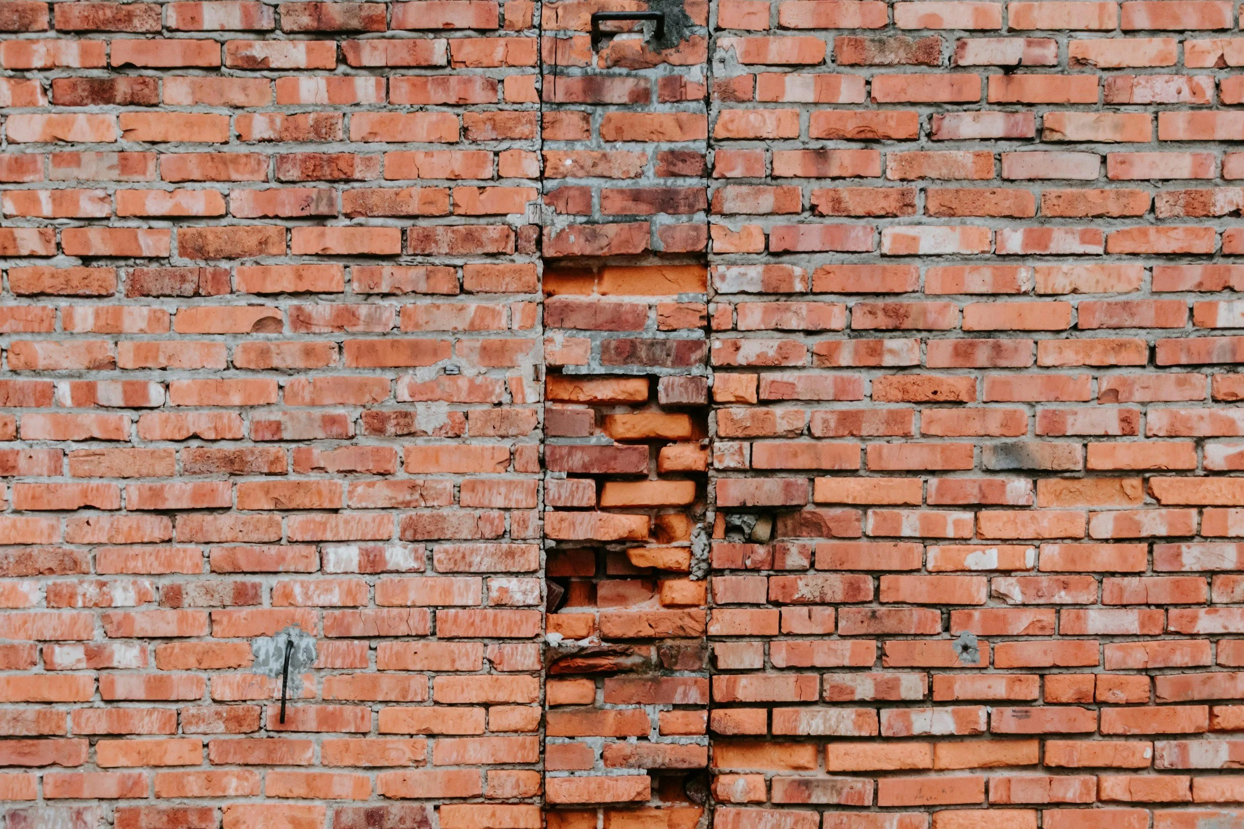 A brick wall with visible cracks and missing bricks.