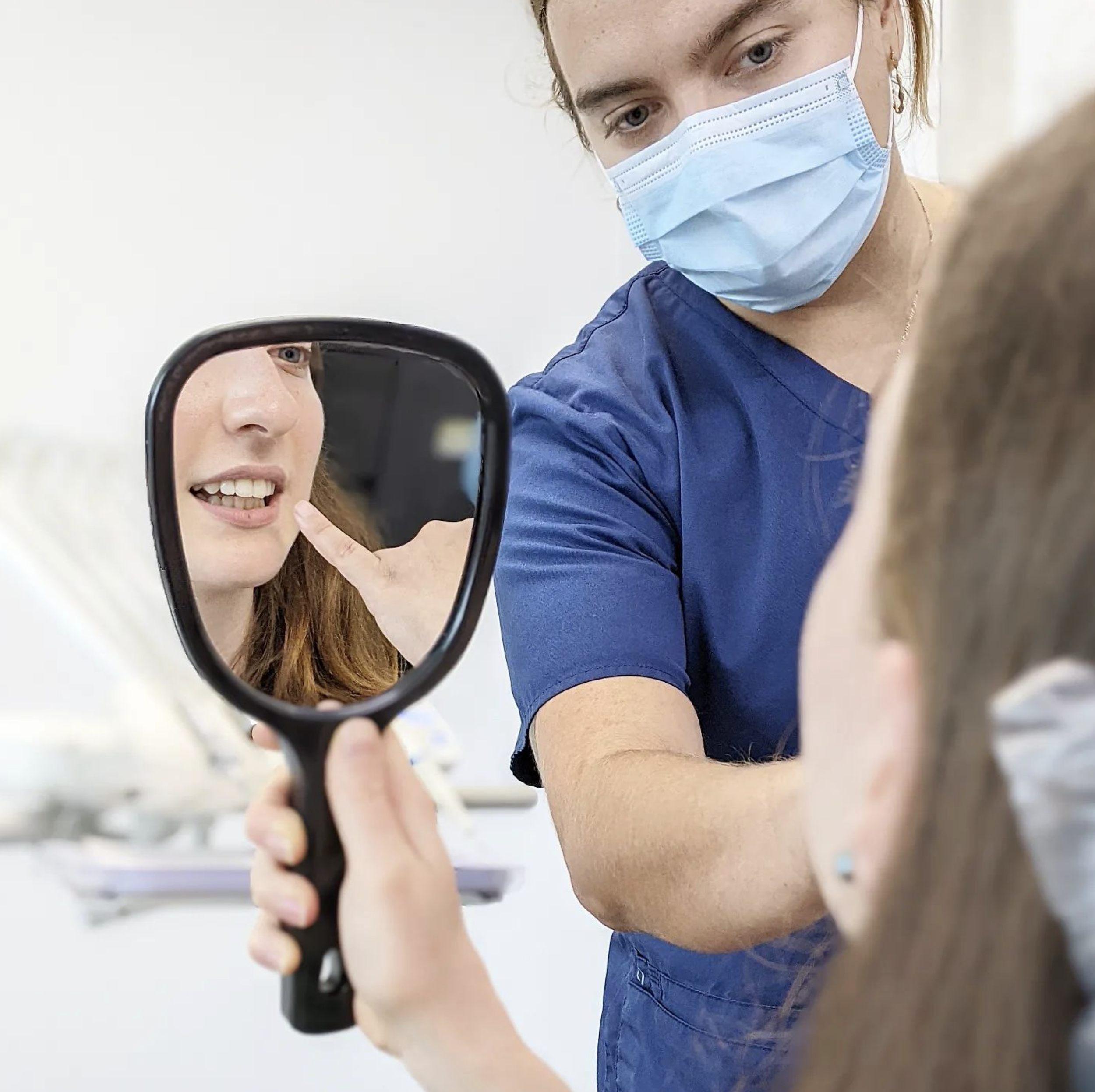 Dentist and patient using a mirror to review dental health during a comprehensive exam at Dee Why Dental.