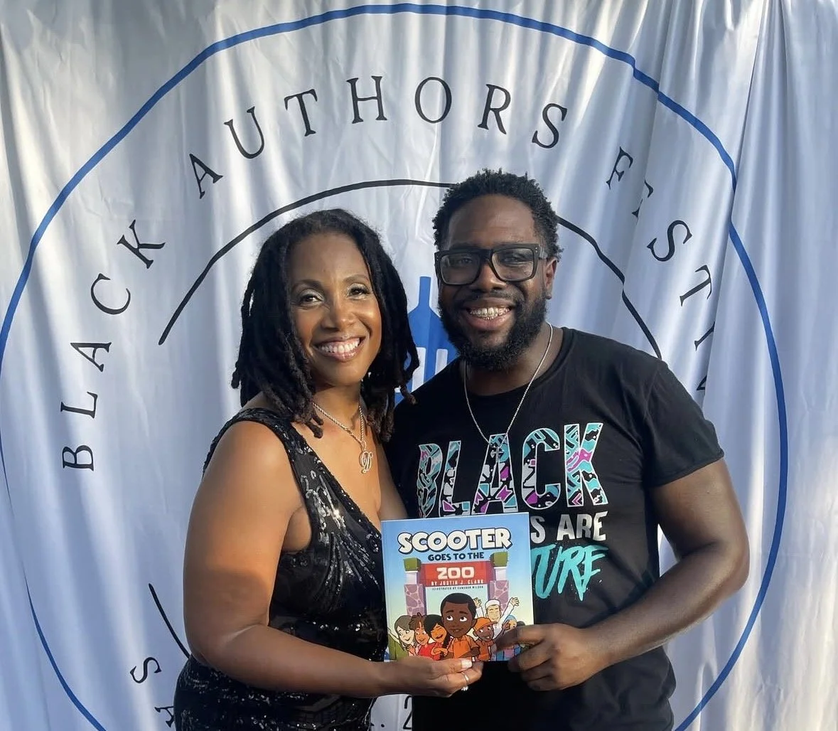 Darlene and a vendor holding up one of his books -  titled 'Scooter Goes to the Zoo' by Justice Clark.