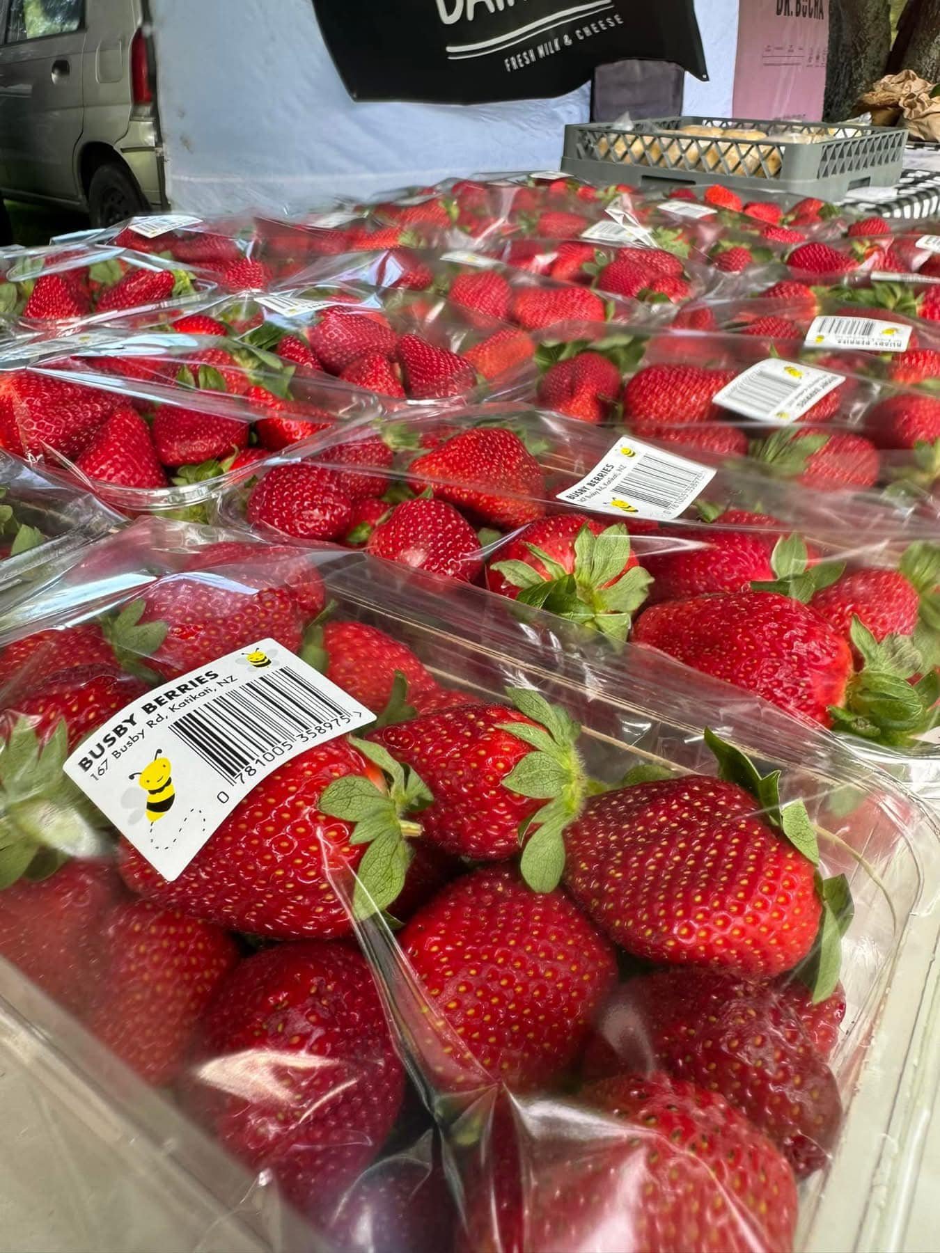 Fresh strawberries in plastic containers on a market stall.