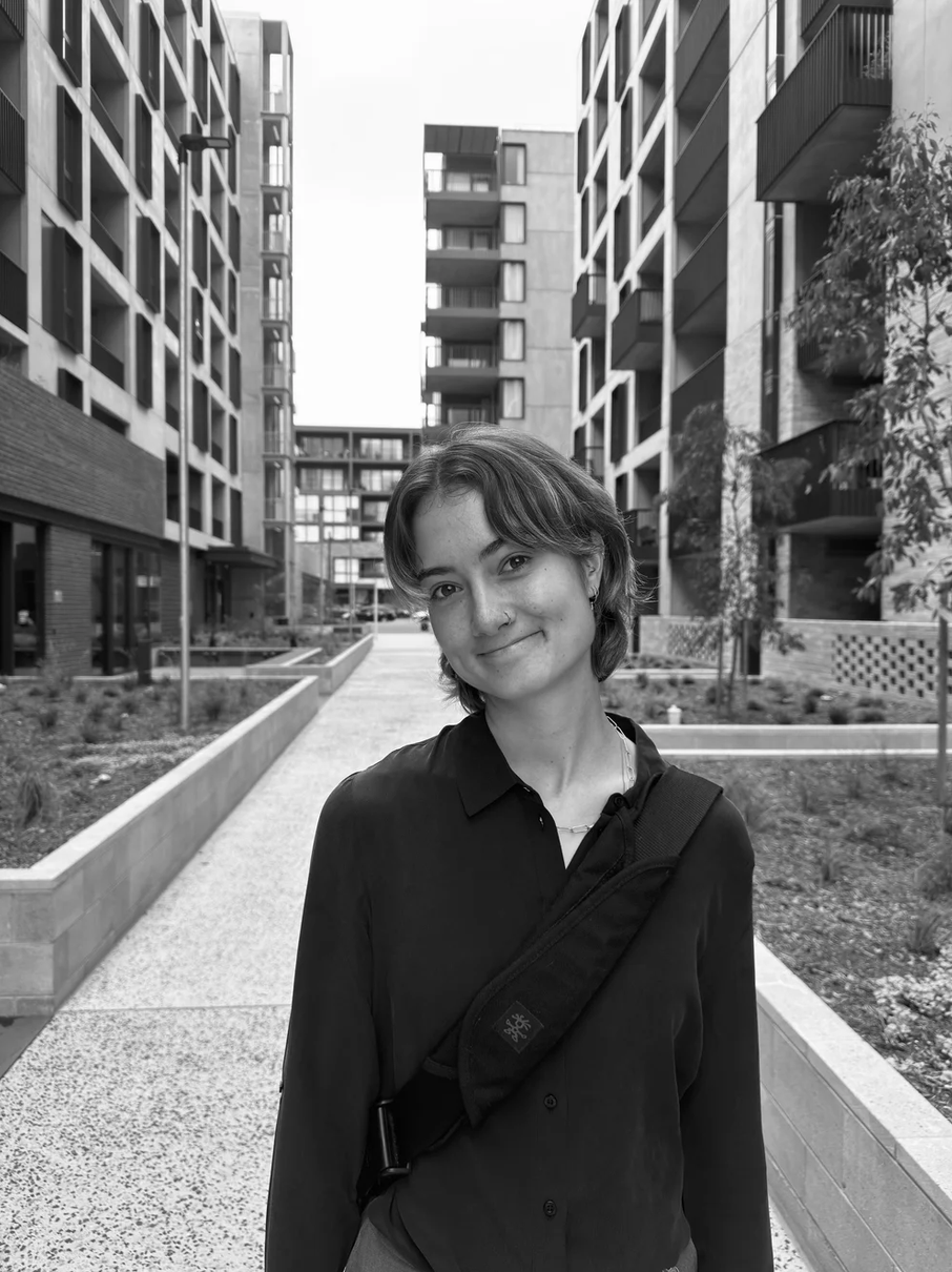 A black and white image of Tuia Suter outside between buildings.