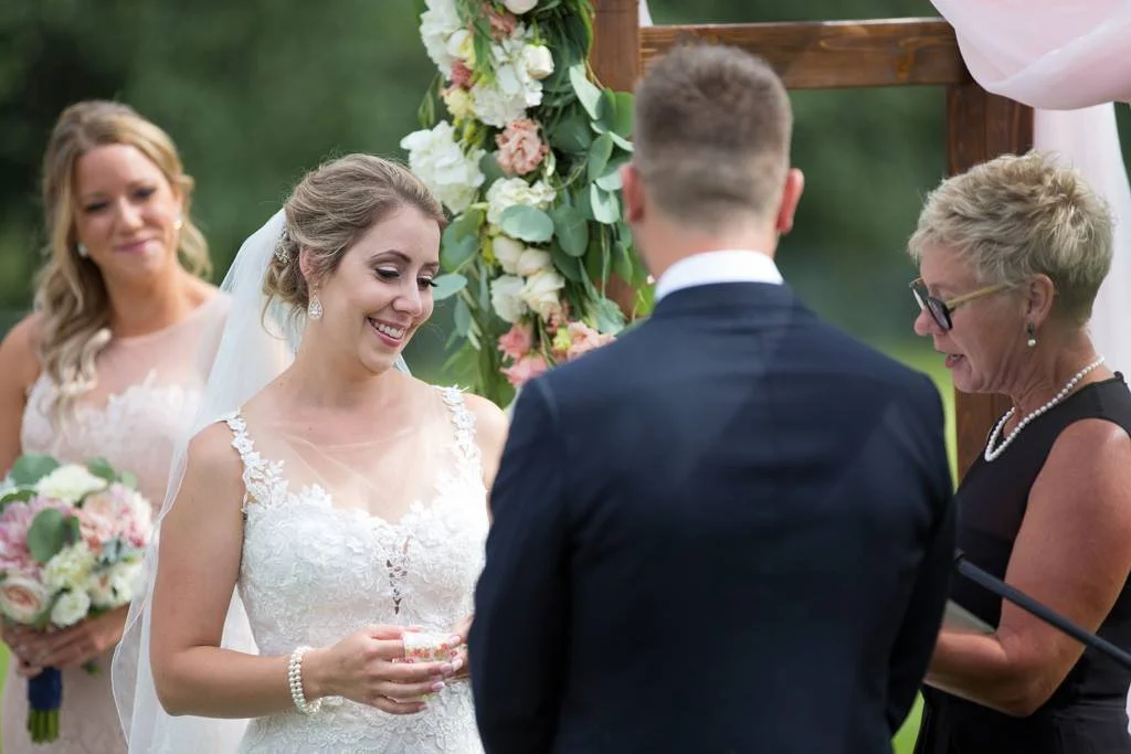 Laurie’s customers, Mariana and Carmen holding hands on a green lawn on their wedding day.