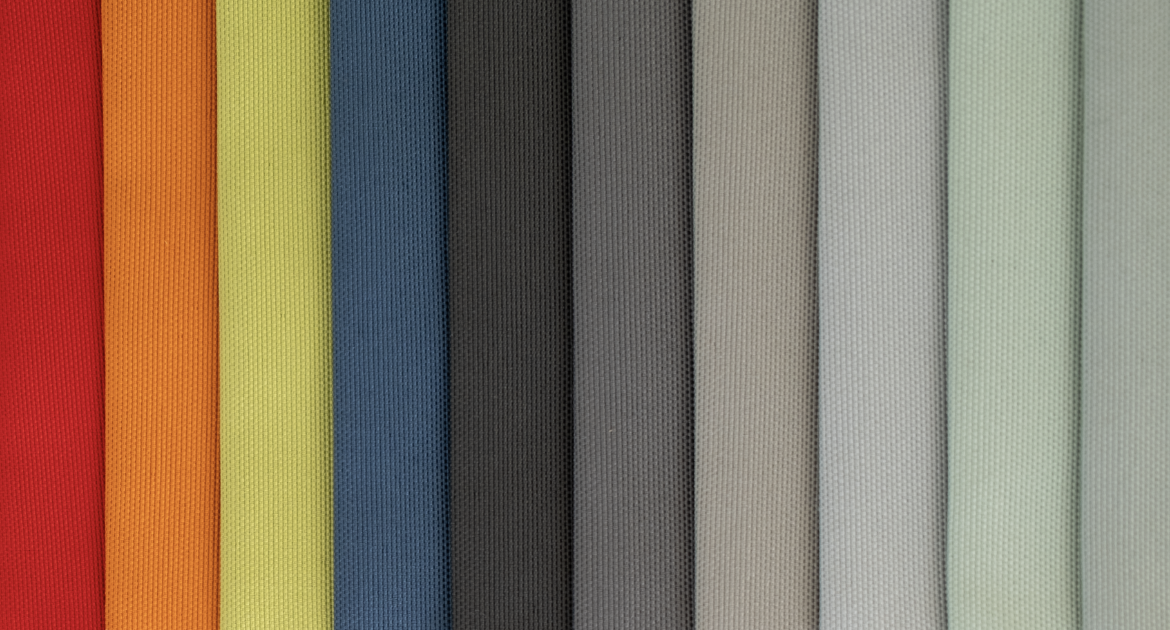 Une rangée de tissus de différentes couleurs, allant du rouge à gauche au gris clair à droite, avec une texture en relief.