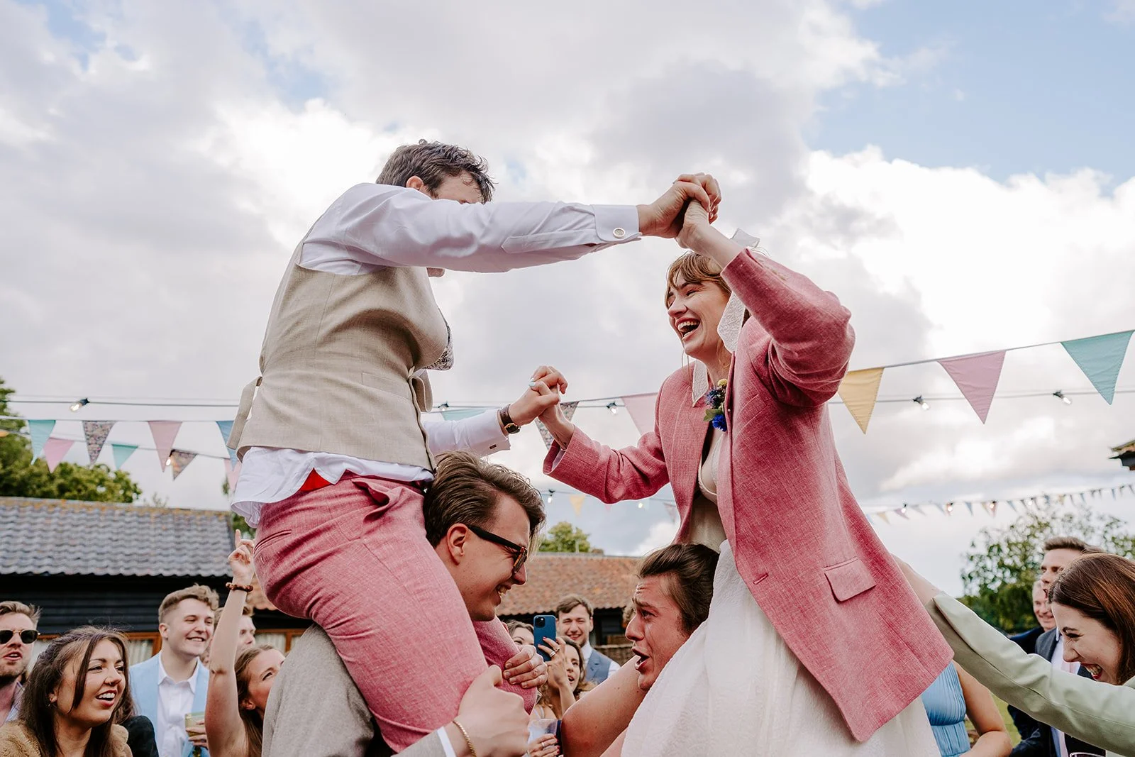 a couple dance both wearing pink suits on their wedding day