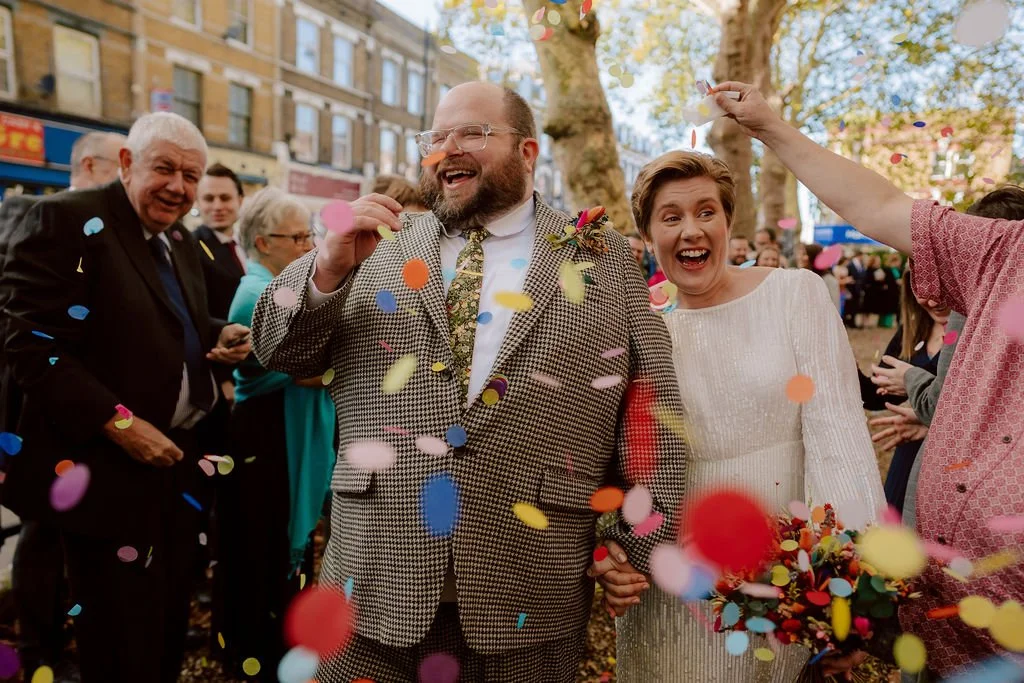 bride and groom beaming at confetti being thrown outside hackney round chapel