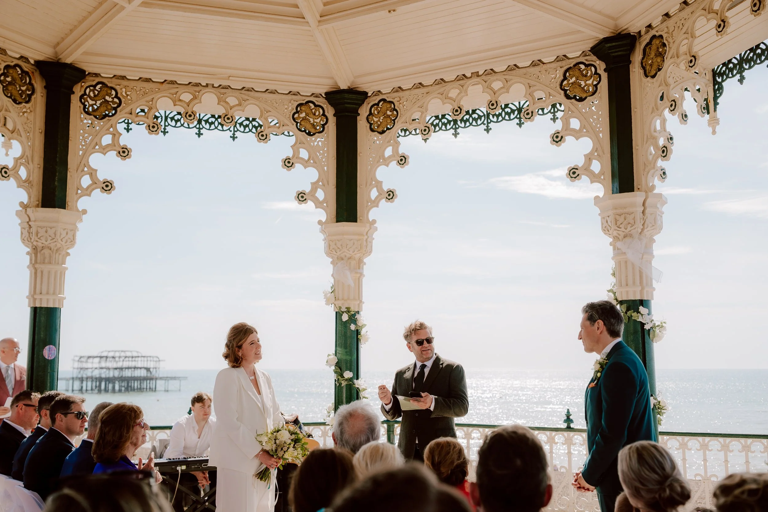 a friend gives a ready on brighton bandstand with the west pier in view