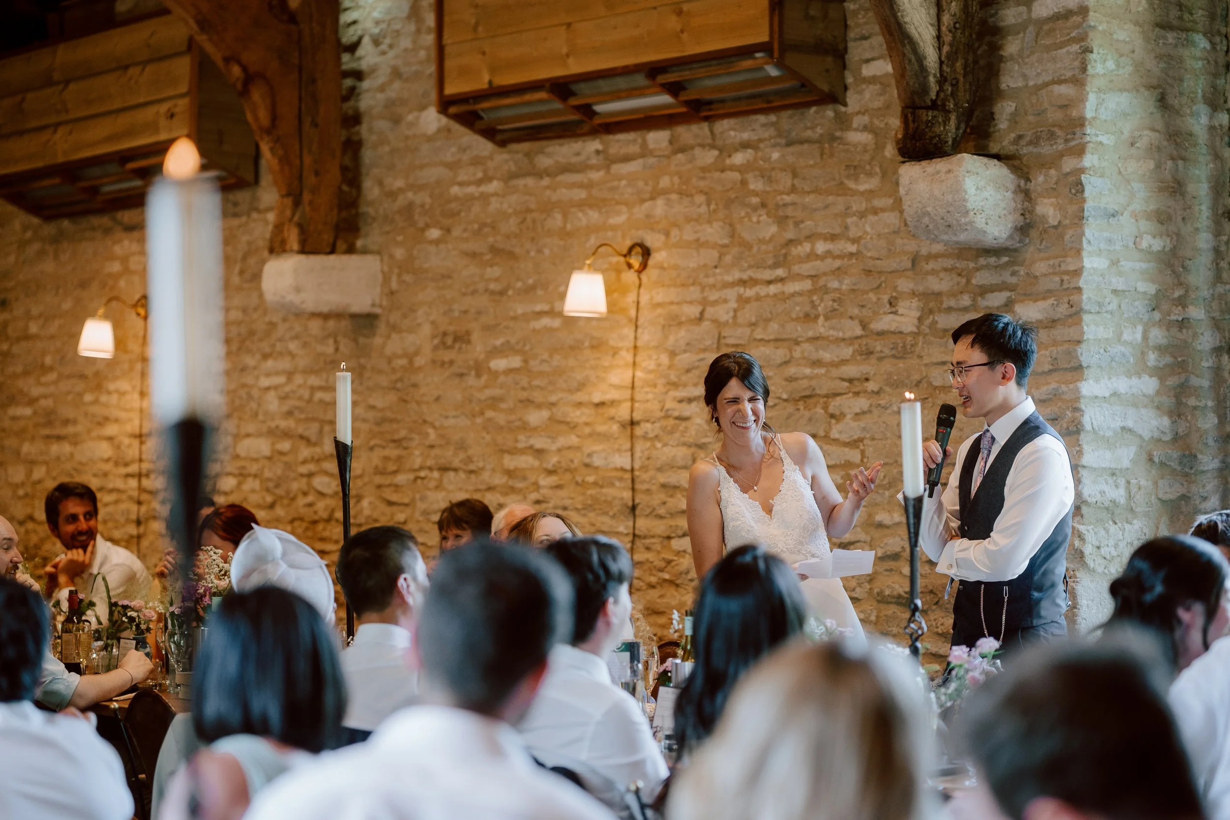 a couple laugh during their speeches at a wedding at Tythe Barn, Launton