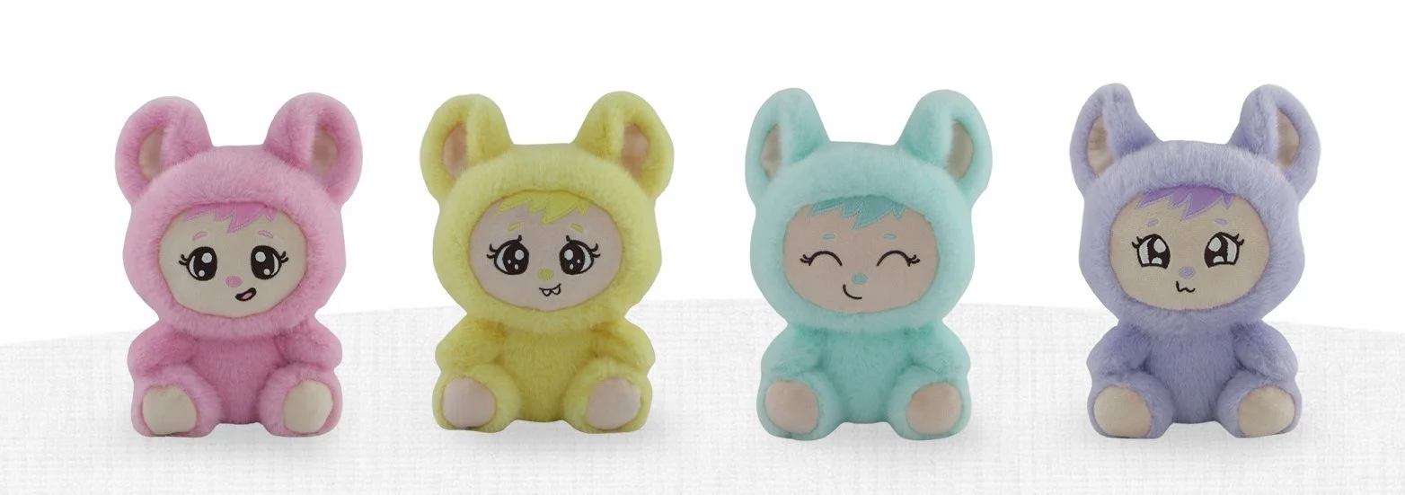 Four adorable Zuzu and Friendz stuffed animal toys with embroidered faces and fuzzy bear-like outfits in pink, yellow, blue, and purple, sitting in a row on a white surface.