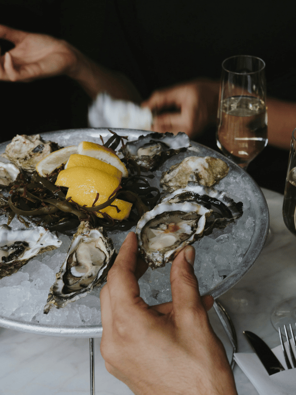 Platter of oysters, hands and champagne flute