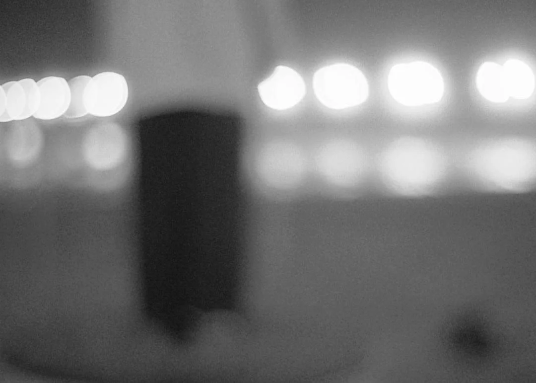 Blurred black object on the ground with bright circular lights in the background.