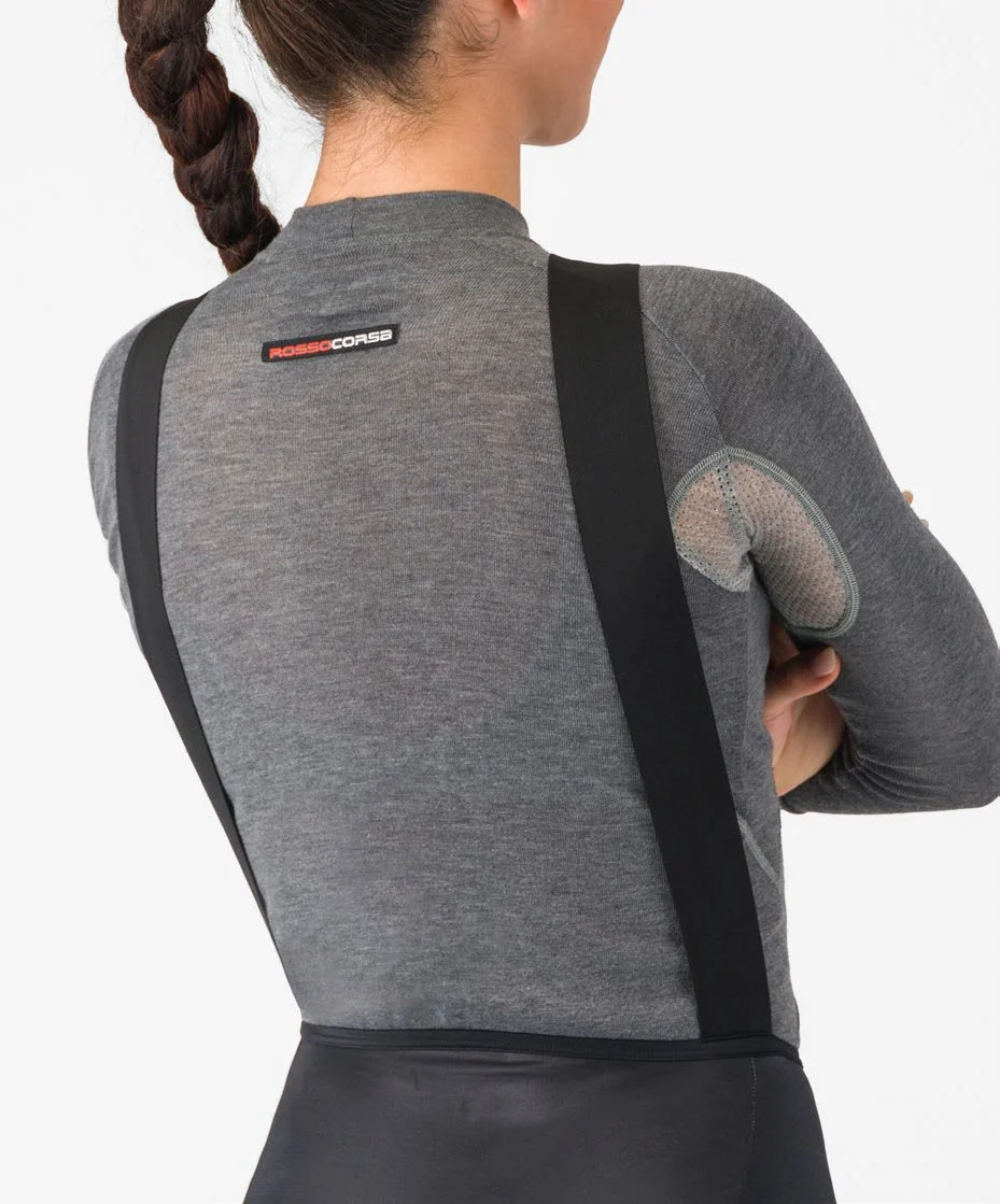 De achtergrond van de afbeelding is wit. Een vrouw met een paardenstaart draagt een winters ondershirt met lange fietsbroek met een logo dat zegt 'ROSCO CORSA' op de achterkant.