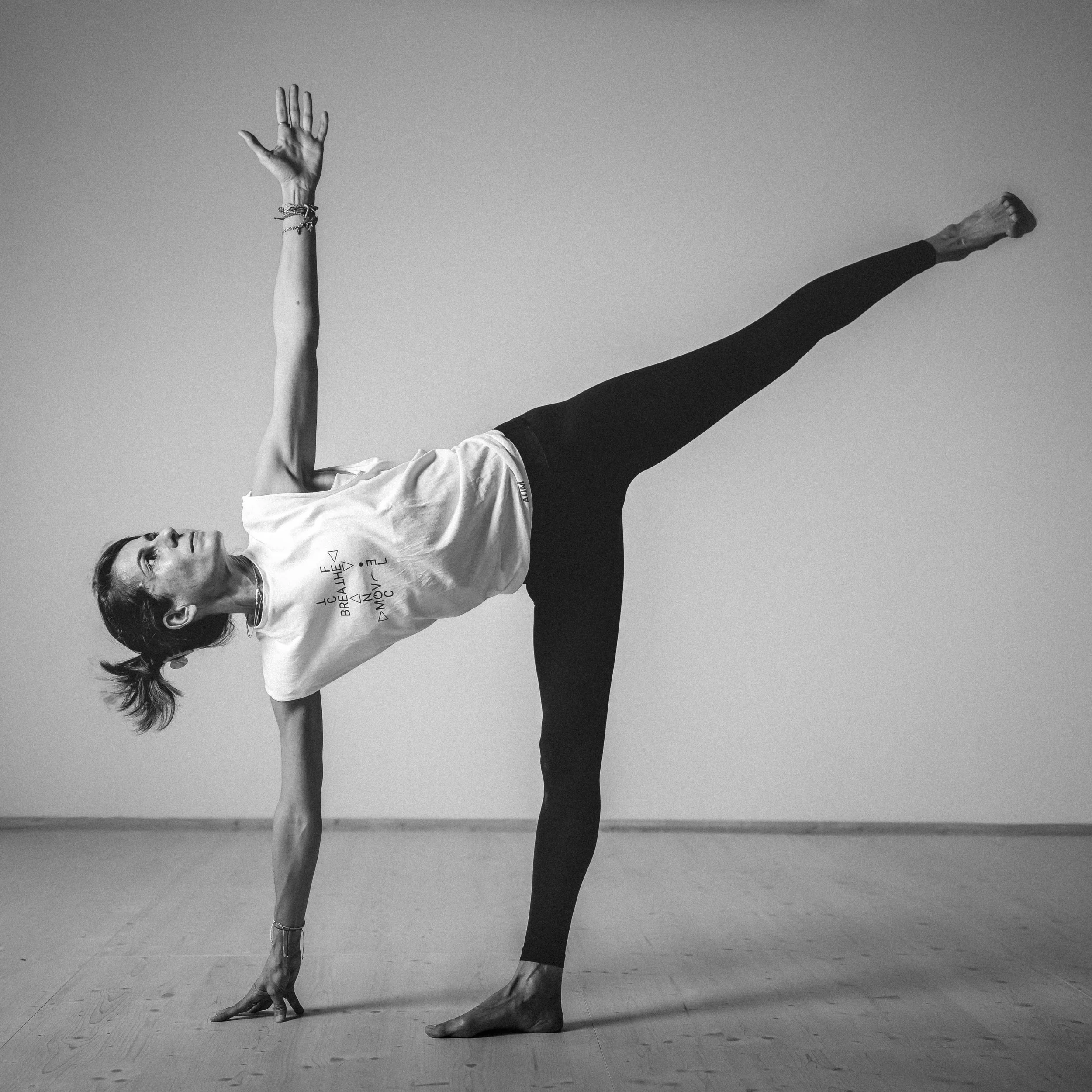 Frau macht Yoga-Übung auf Holzboden, einzeln, schwarzen Leggings und T-Shirt, im Raum, schwarz-weiß