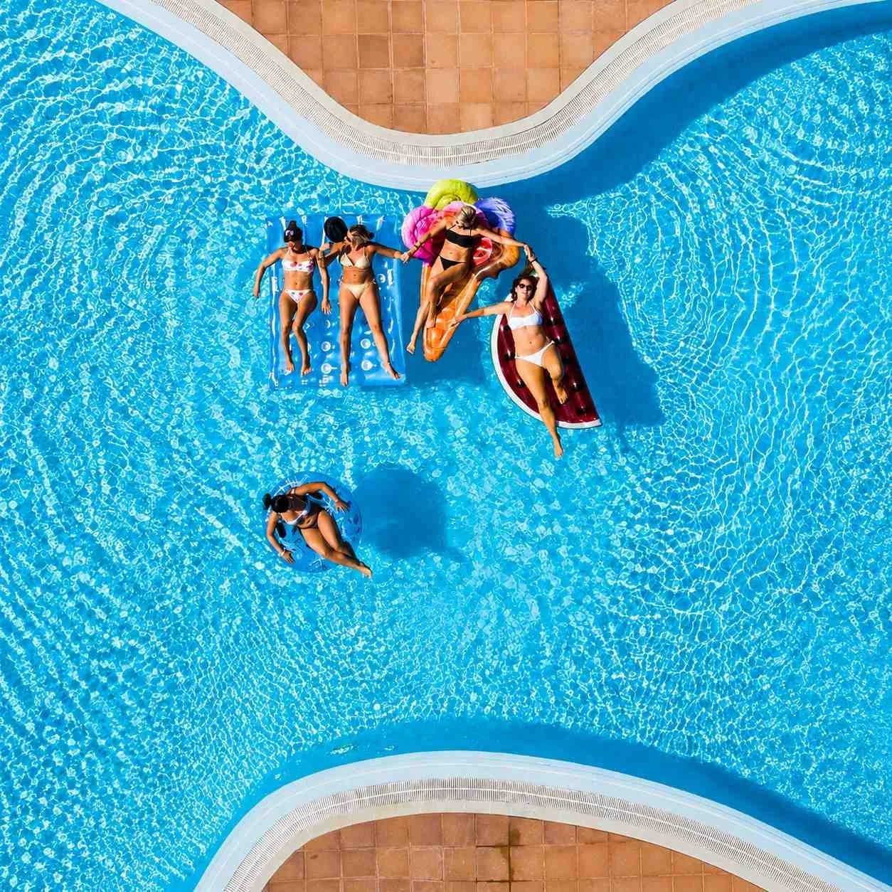 Residents relaxing in a well-maintained community swimming pool, showcasing HOA-managed neighborhood amenities.