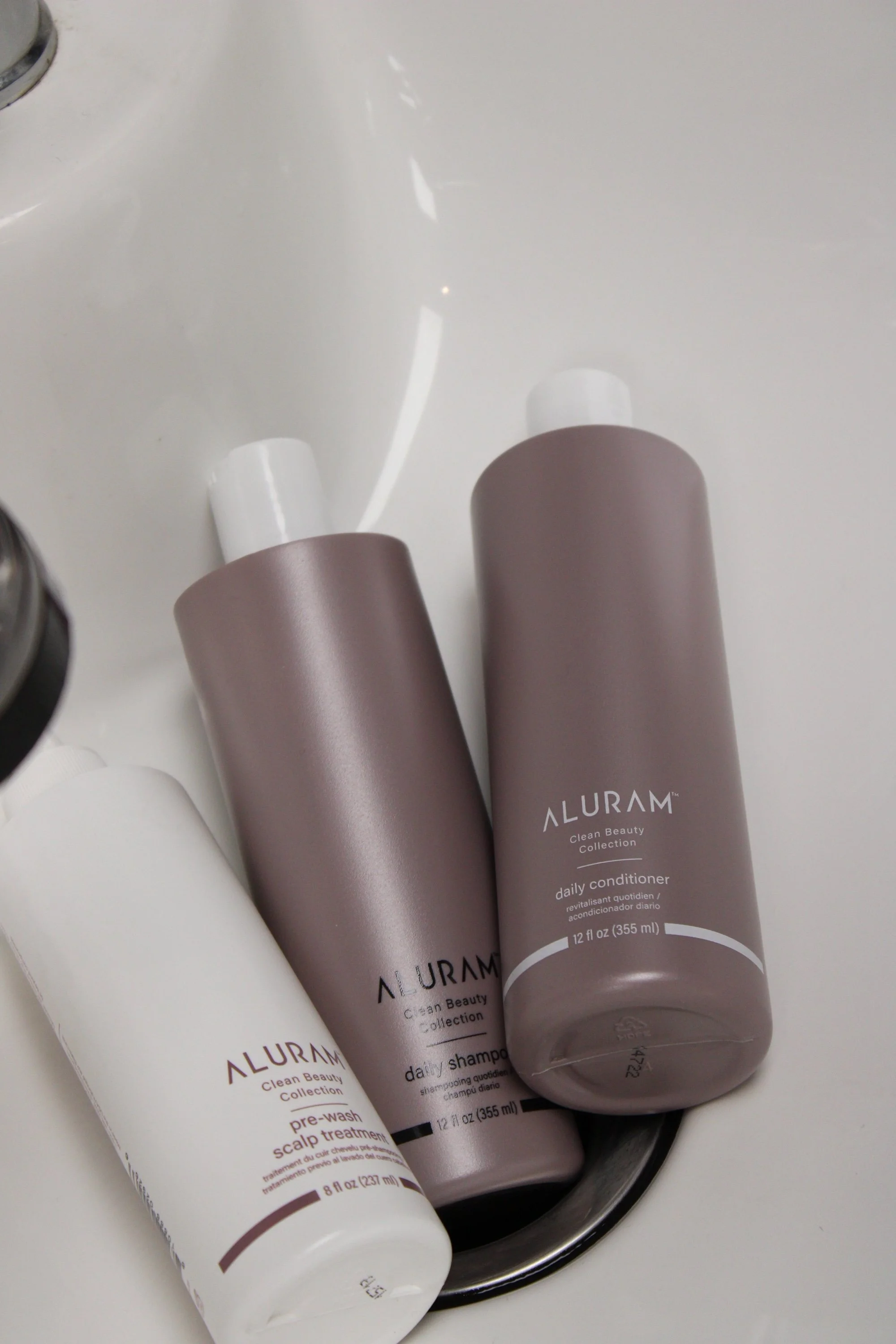 Aluram hair care products laying in sink.