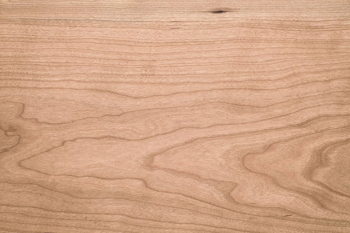 A close-up of a light-colored wooden surface showing natural wood grain patterns.