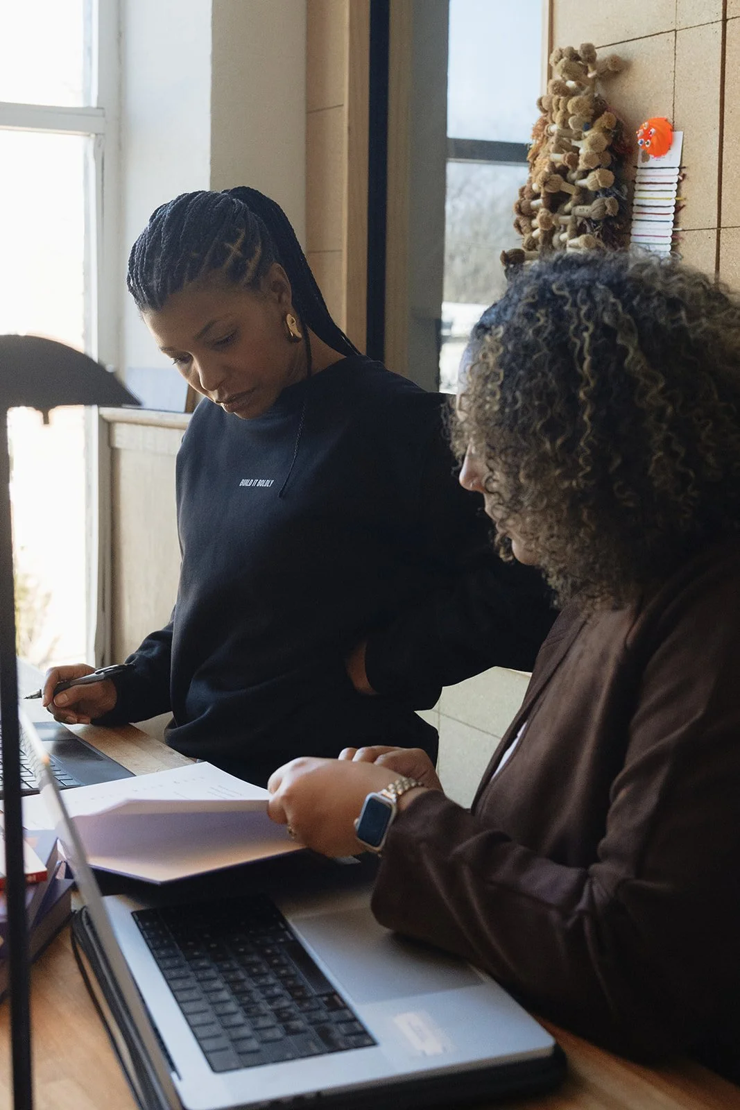 Dr. Kimberly McGlonn reviewing a leadership workbook with a colleague at a desk