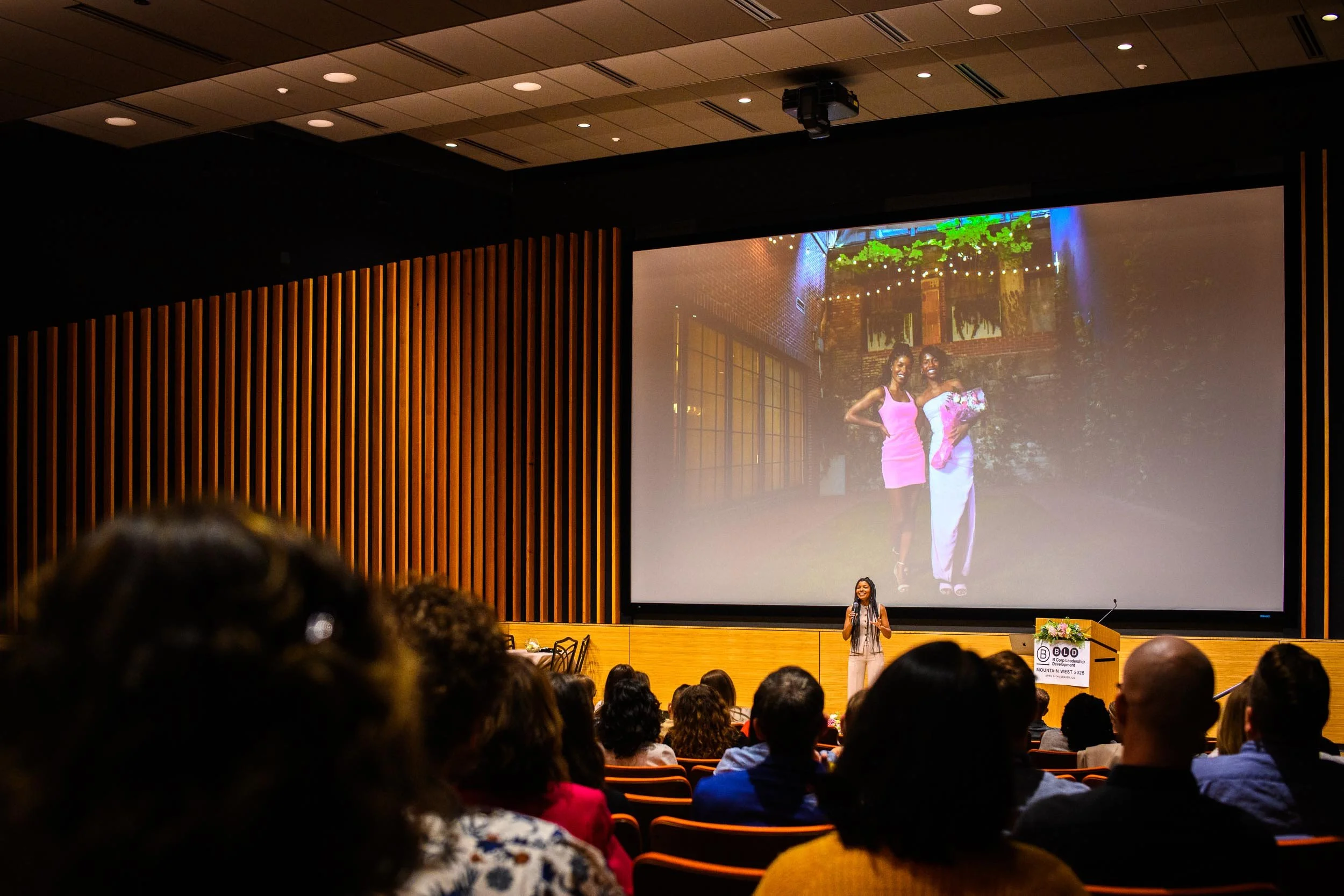 Dr. Kimberly McGlonn speaking to a large audience in an auditorium during a keynote presentation