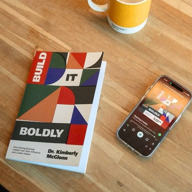Build It Boldly book beside a smartphone playing the audiobook