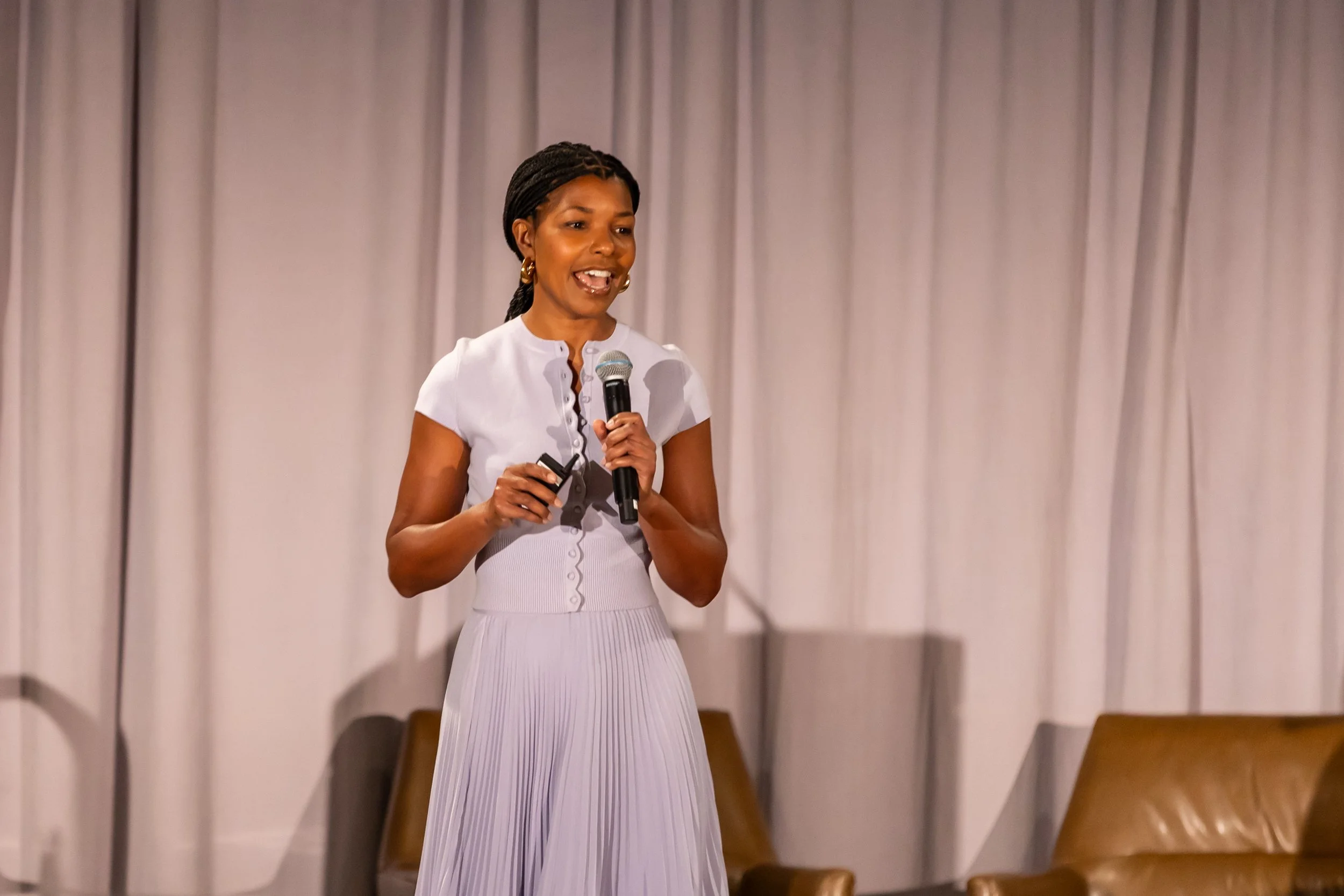 professional-speaking-event.jpg Dr. Kimberly McGlonn presenting on stage with a microphone at a professional speaking event